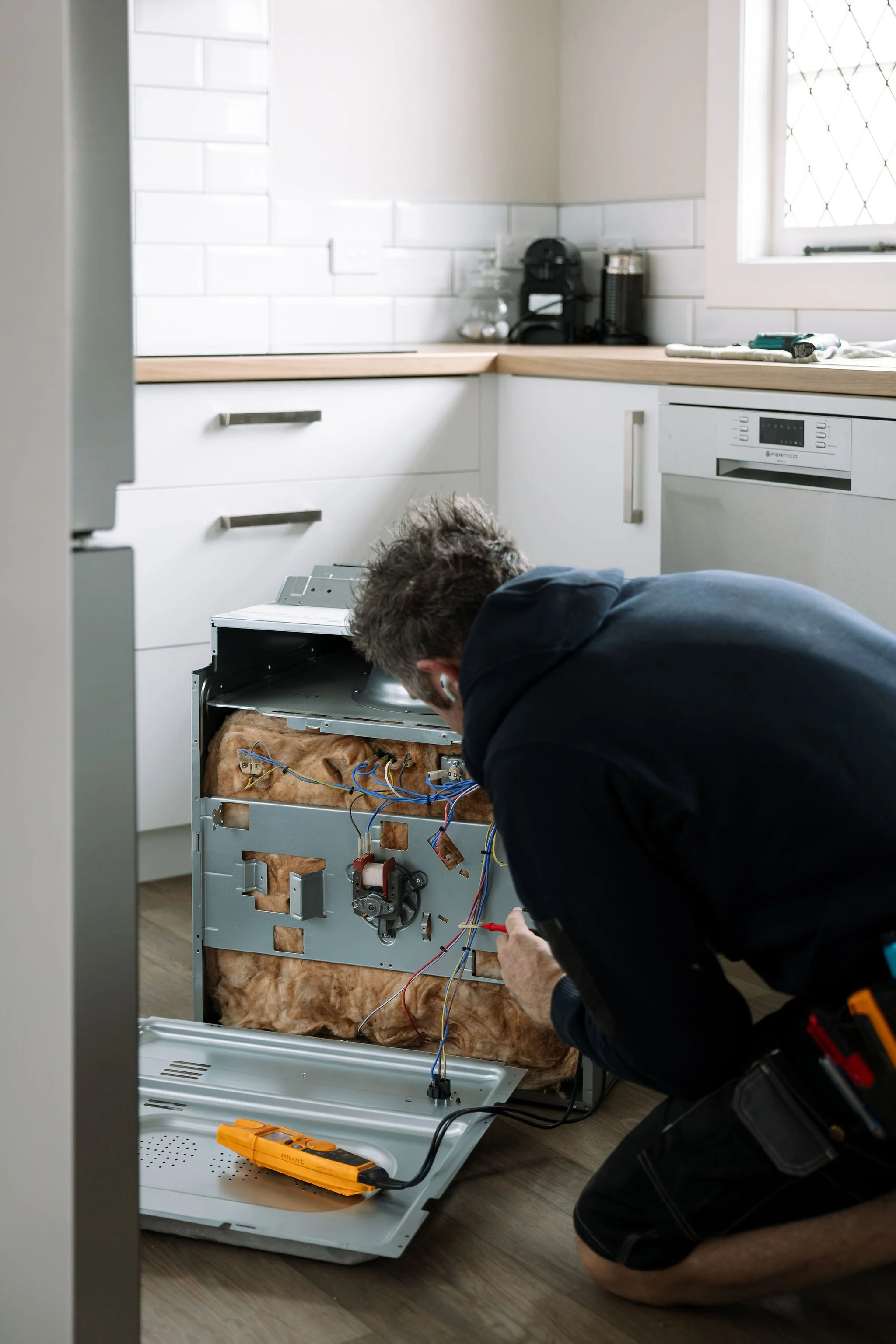 Electrician installing a kitchen appliance in a Palmerston North home