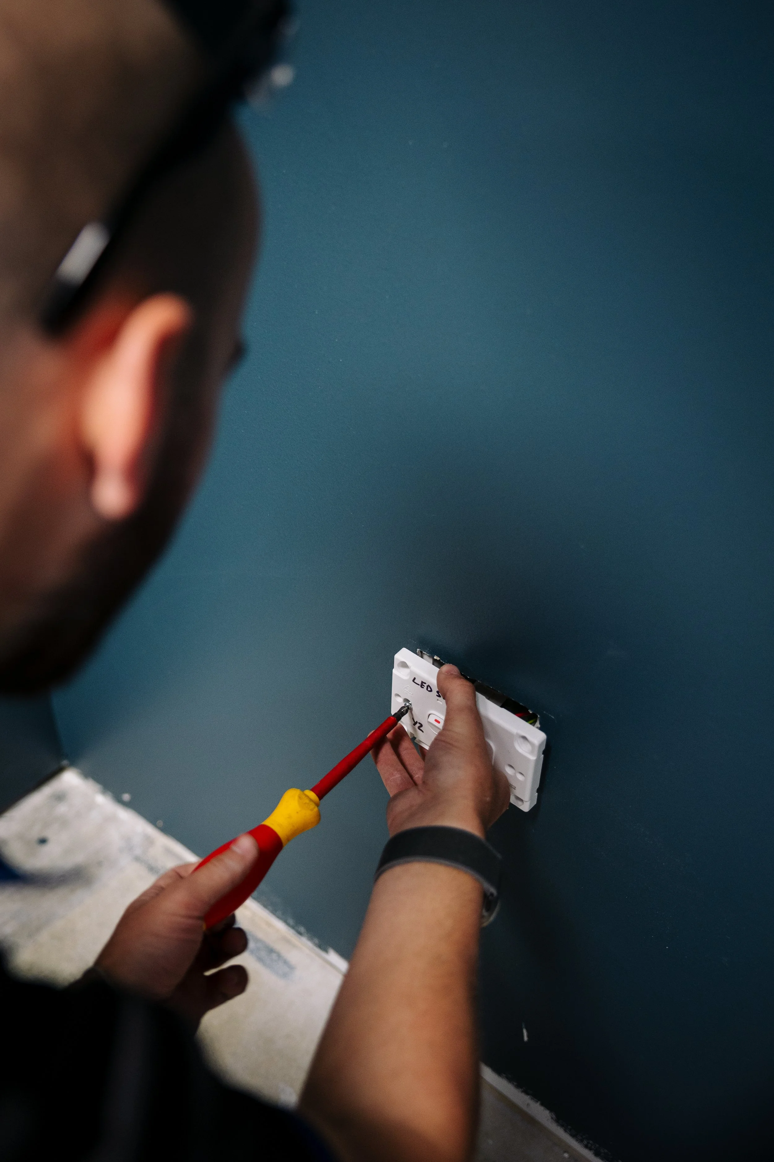 Electrician wiring a light switch during a commercial fitout