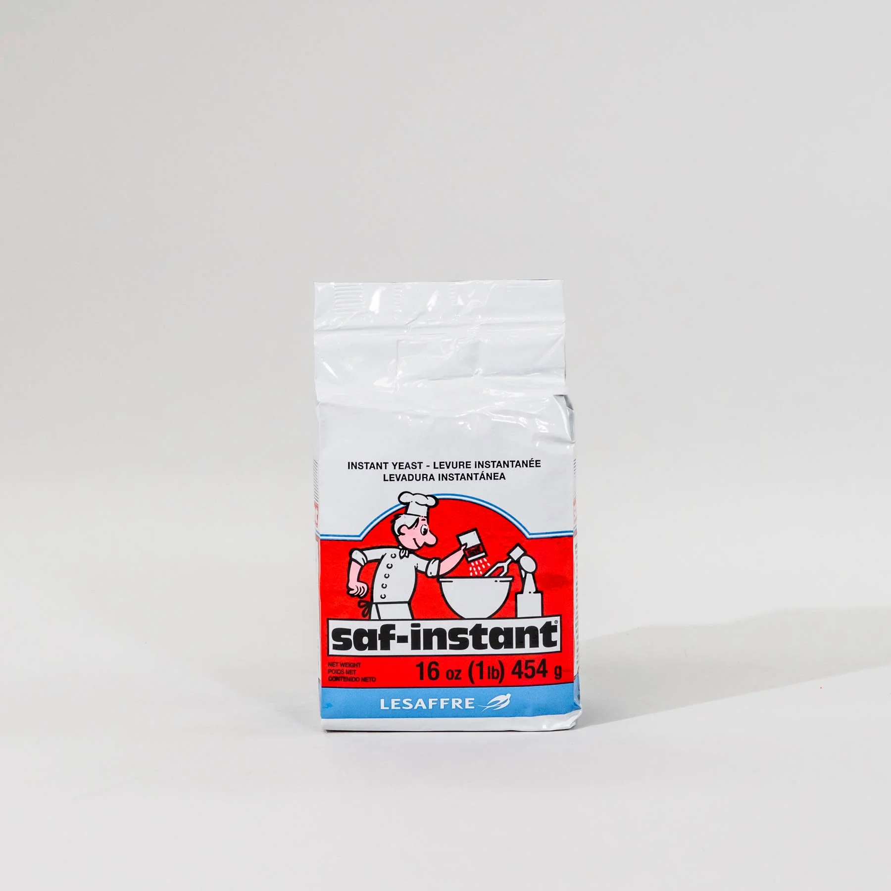 A bag of SAF-Instant leavening yeast with a cartoon chef pouring yeast into a bowl, placed on a plain white background.