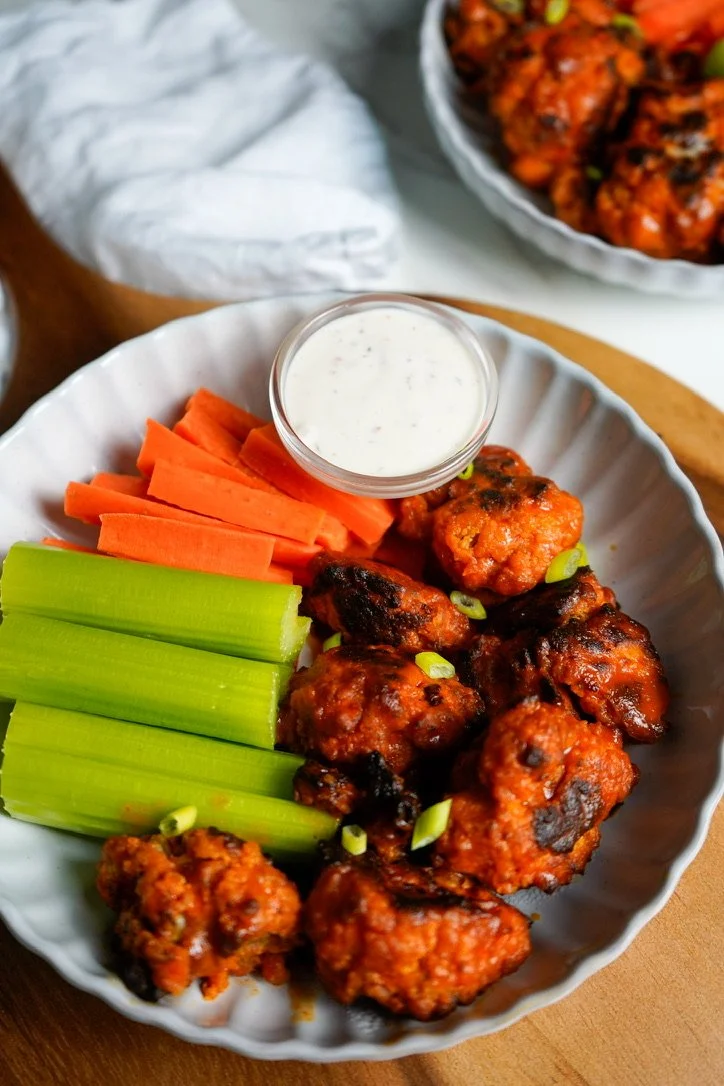Baked buffalo cauliflower wings served with celery sticks, carrot sticks, and a side of ranch dressing