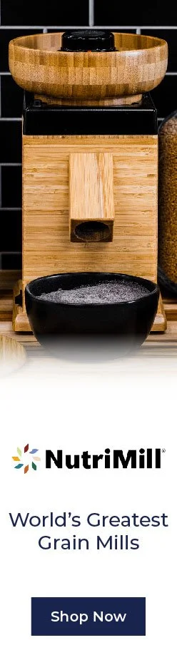 A wooden grain mill with a large round wooden bowl on top, a small opening in the middle, and a black bowl at the bottom, with NutriMill branding and the text "World's Greatest Grain Mills" below.