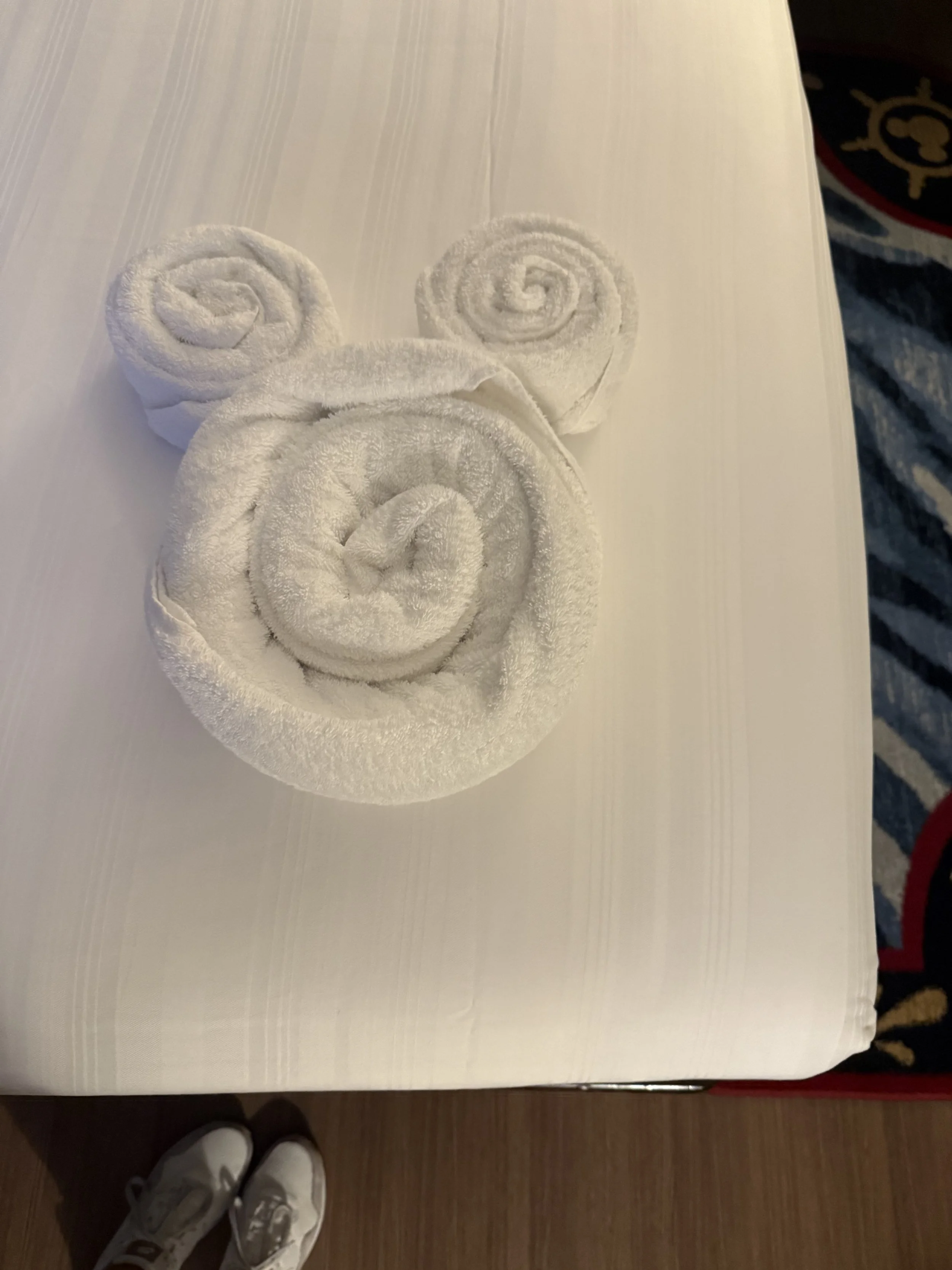 Three towel animals shaped like Mickey Mouse ears arranged on a white table.