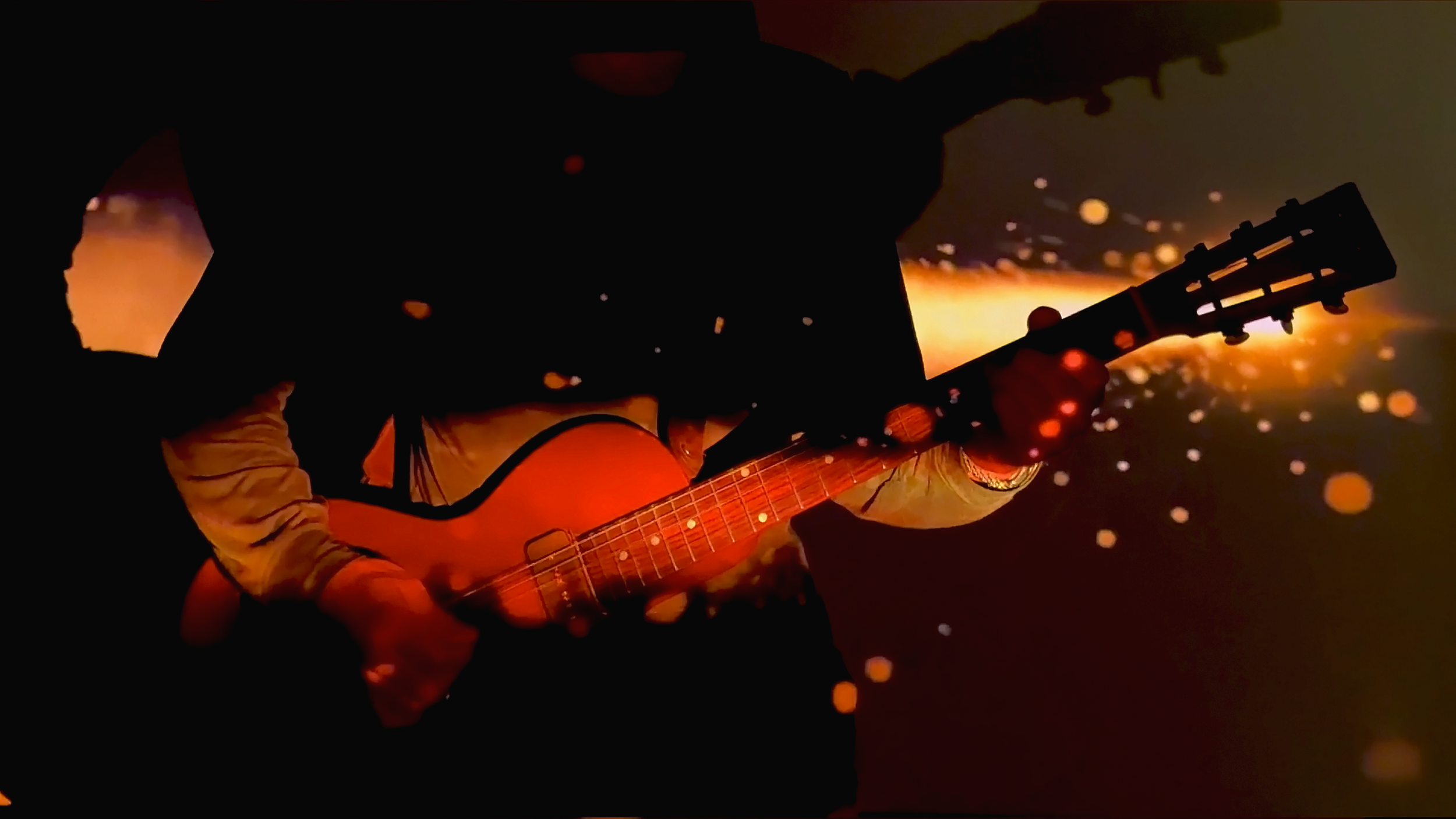 Person playing guitar in silhouette with a vibrant, glowing background and floating sparks.