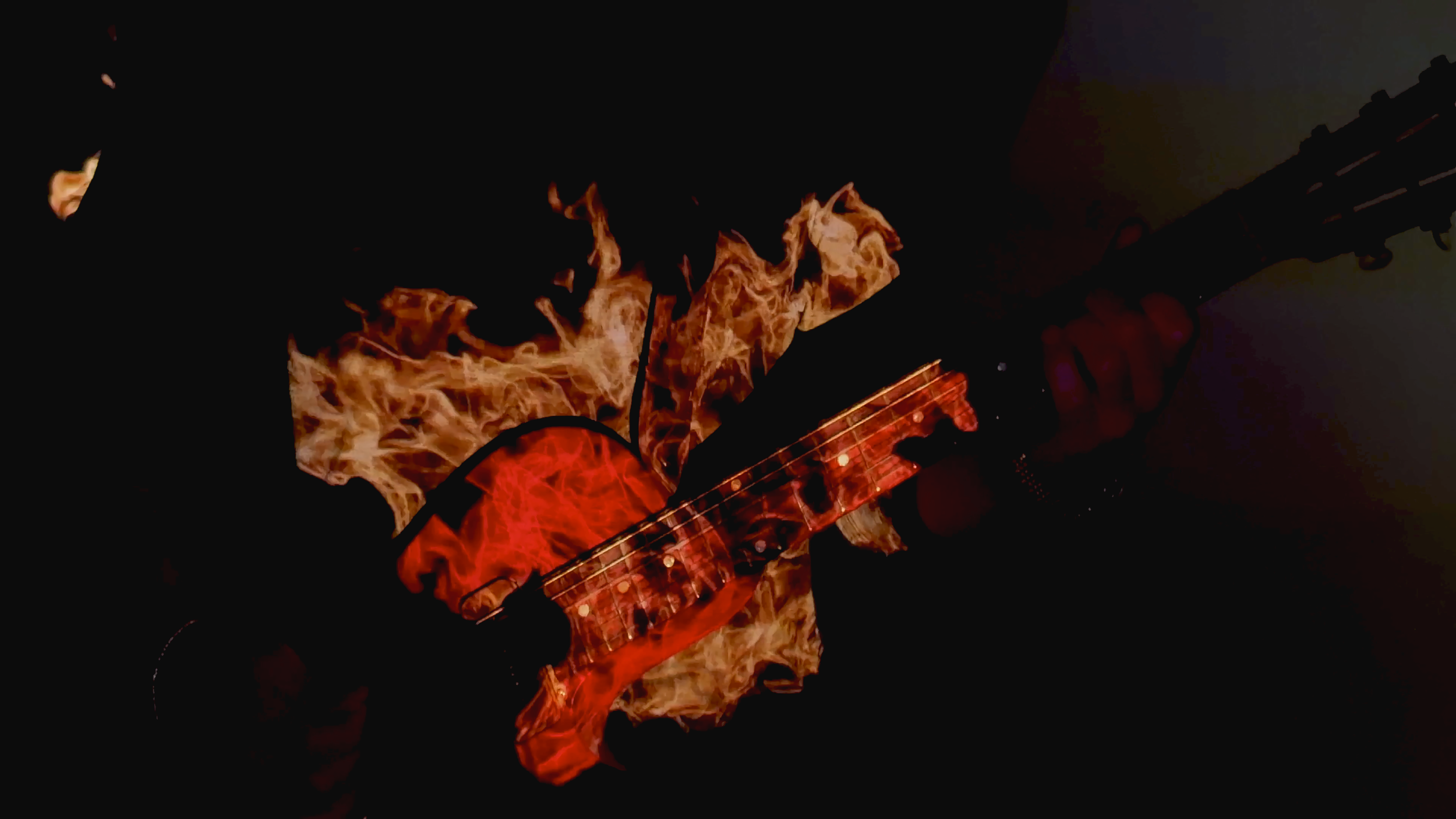 Guitar with flames design on the body being played by a person in a dark setting.