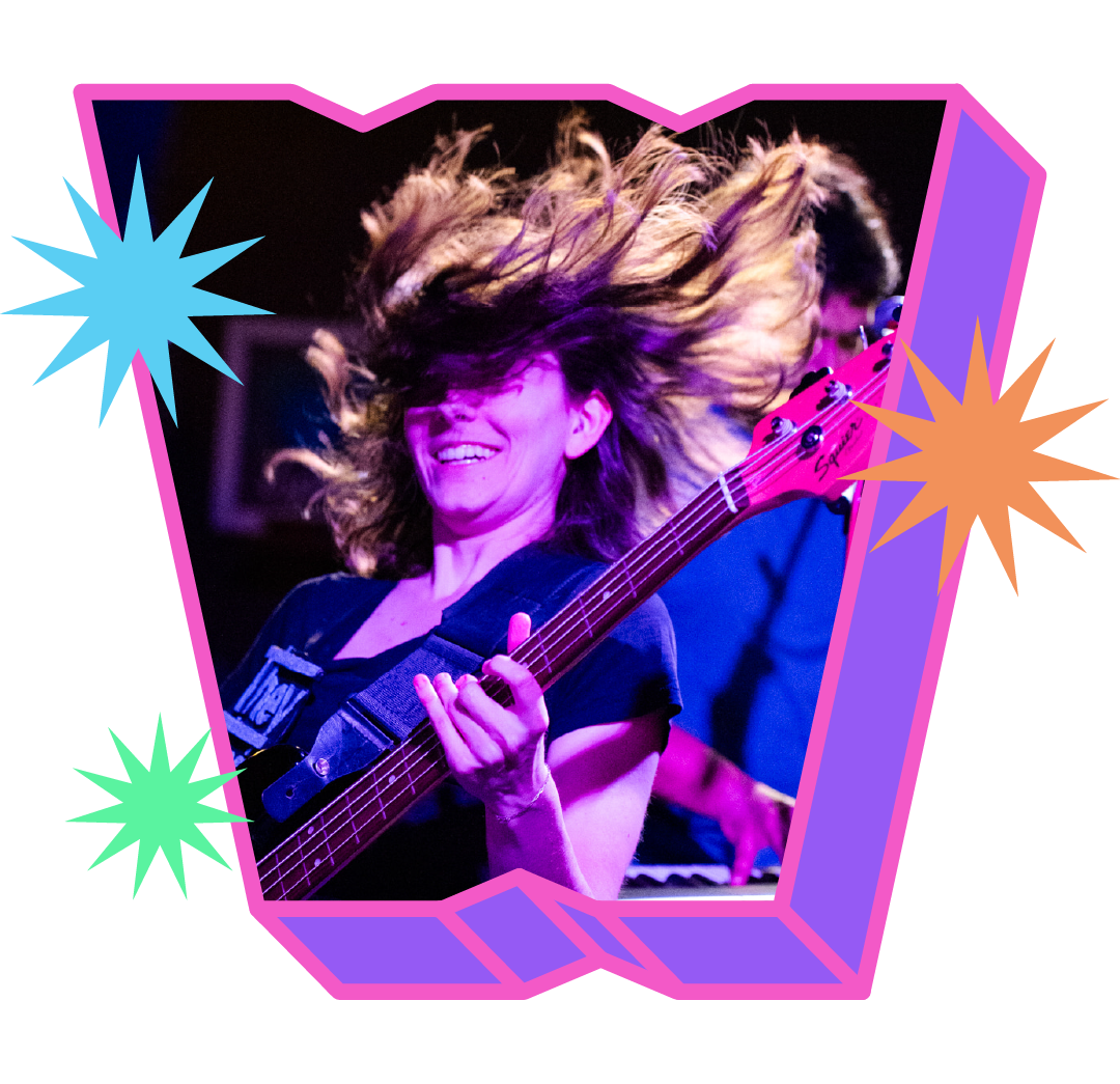 Miss Christine, flinging their dark hair into the air, plays a purple guitar