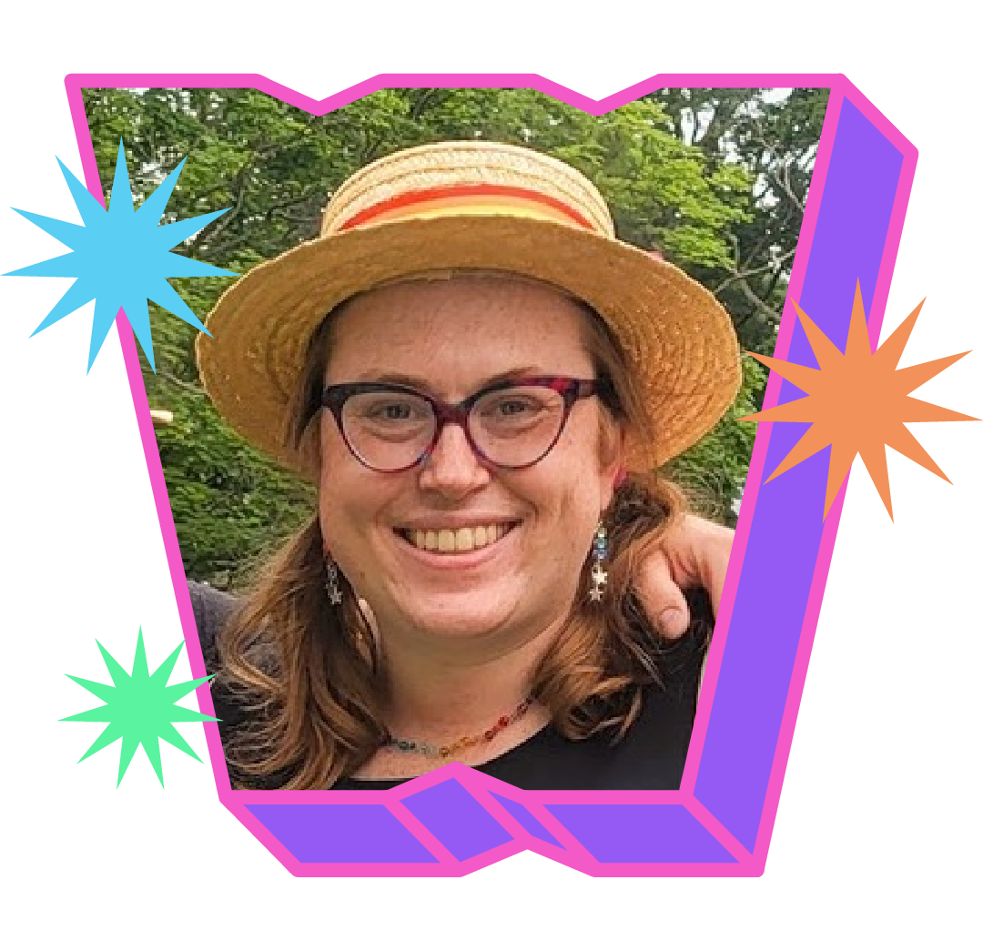 Krys Petrie with shoulder length brown hair and wearing glasses and a boater hat, smiles