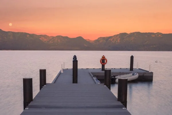 A private pier jutting out into the lake at sunset, overlooking the Sierra Nevada mountains in the background