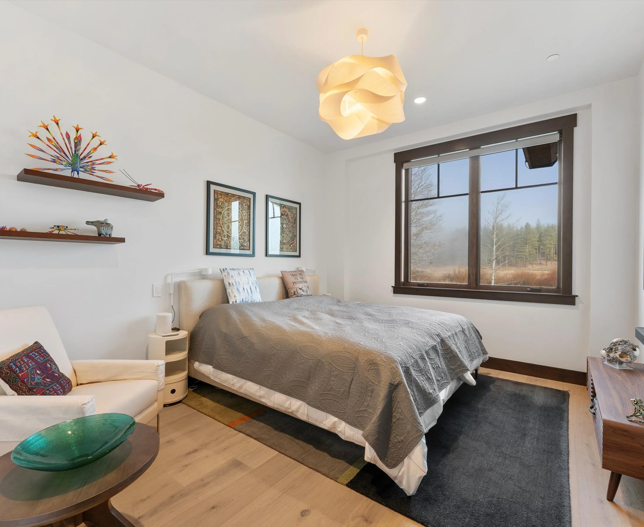 One of Residence 907's three bedrooms, serenely decorated, showcasing a large cozy bed, and a large window letting in natural light