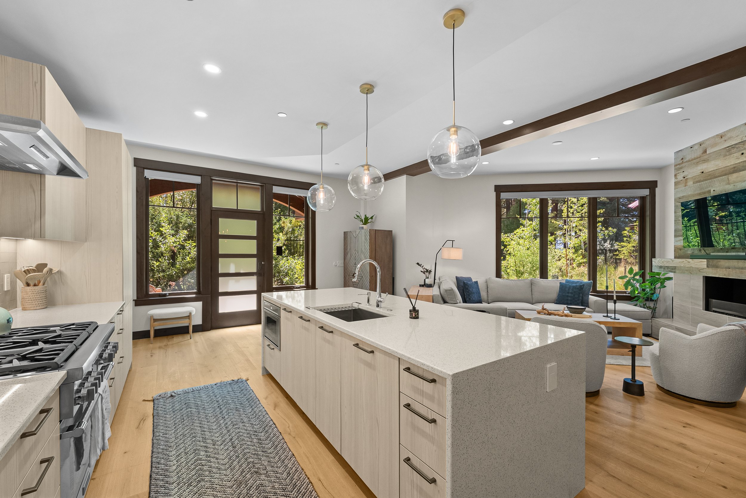 Bright open-concept floor plan featuring a modern kitchen with a large marble tiled island and seating for 4 people, and modern furnishings.