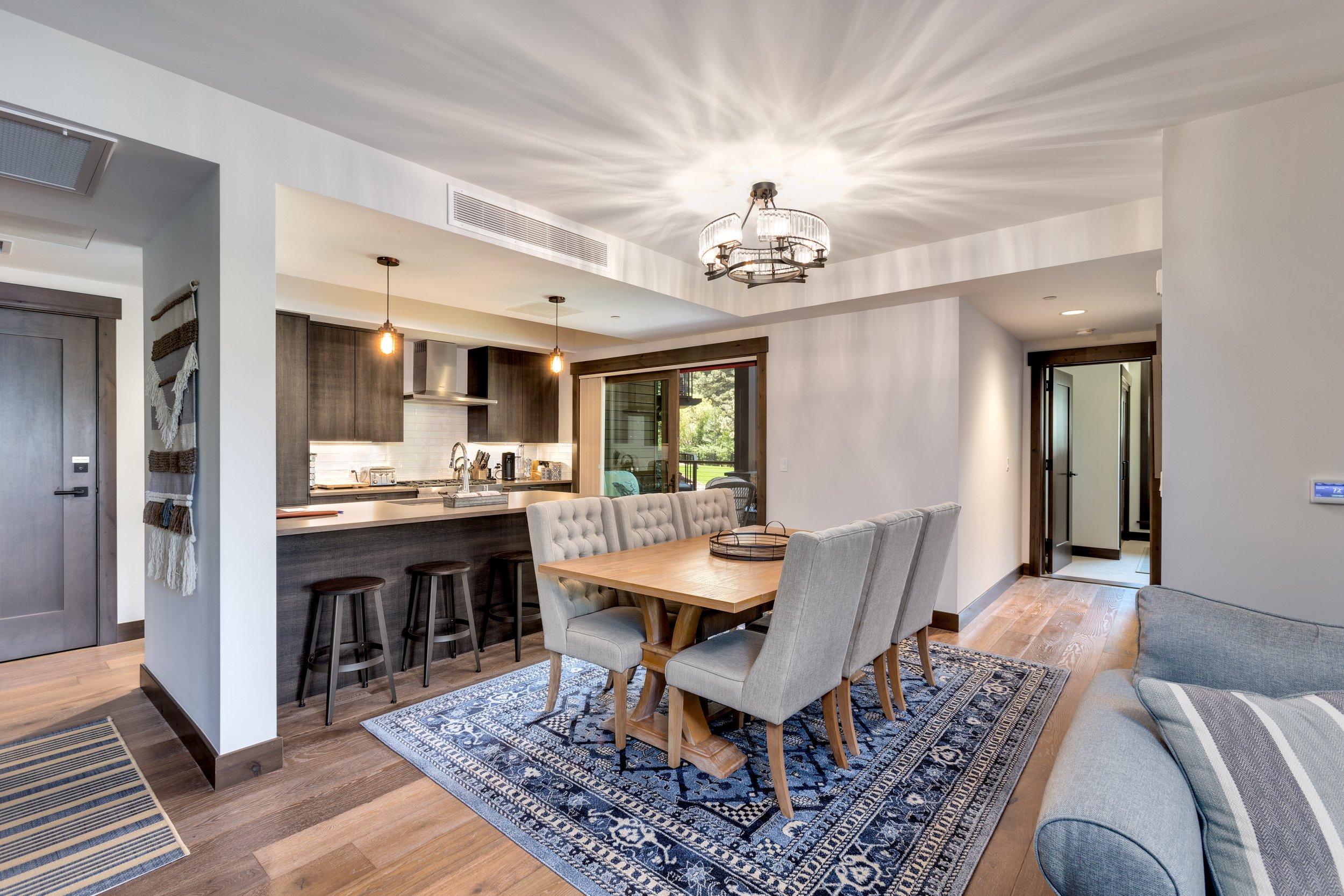 A modern kitchen and dining room with a circular pendant light casting a warm glow over the area.