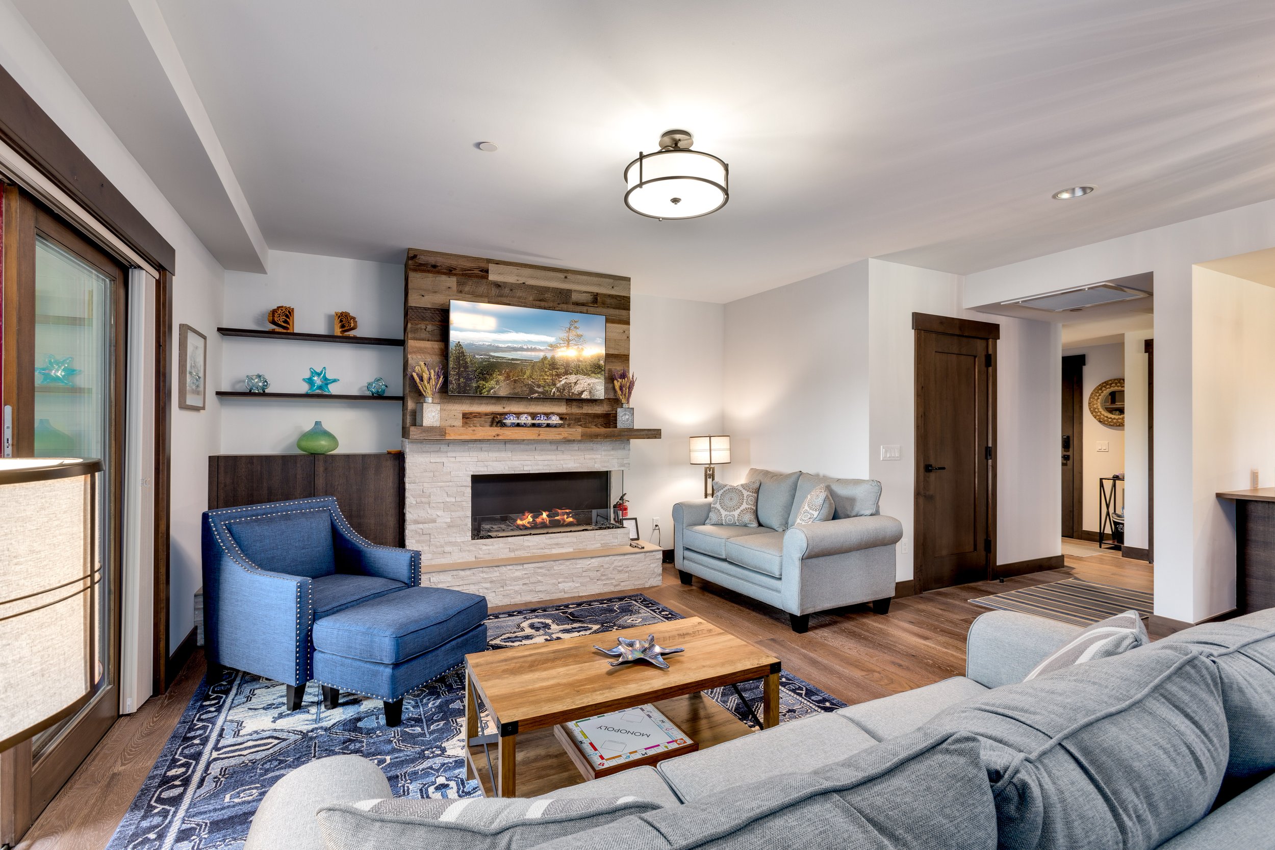 Tahoe Beach Club’s vacation rental features a cozy living room with a fireplace as the focal point, adorned with blue chairs.