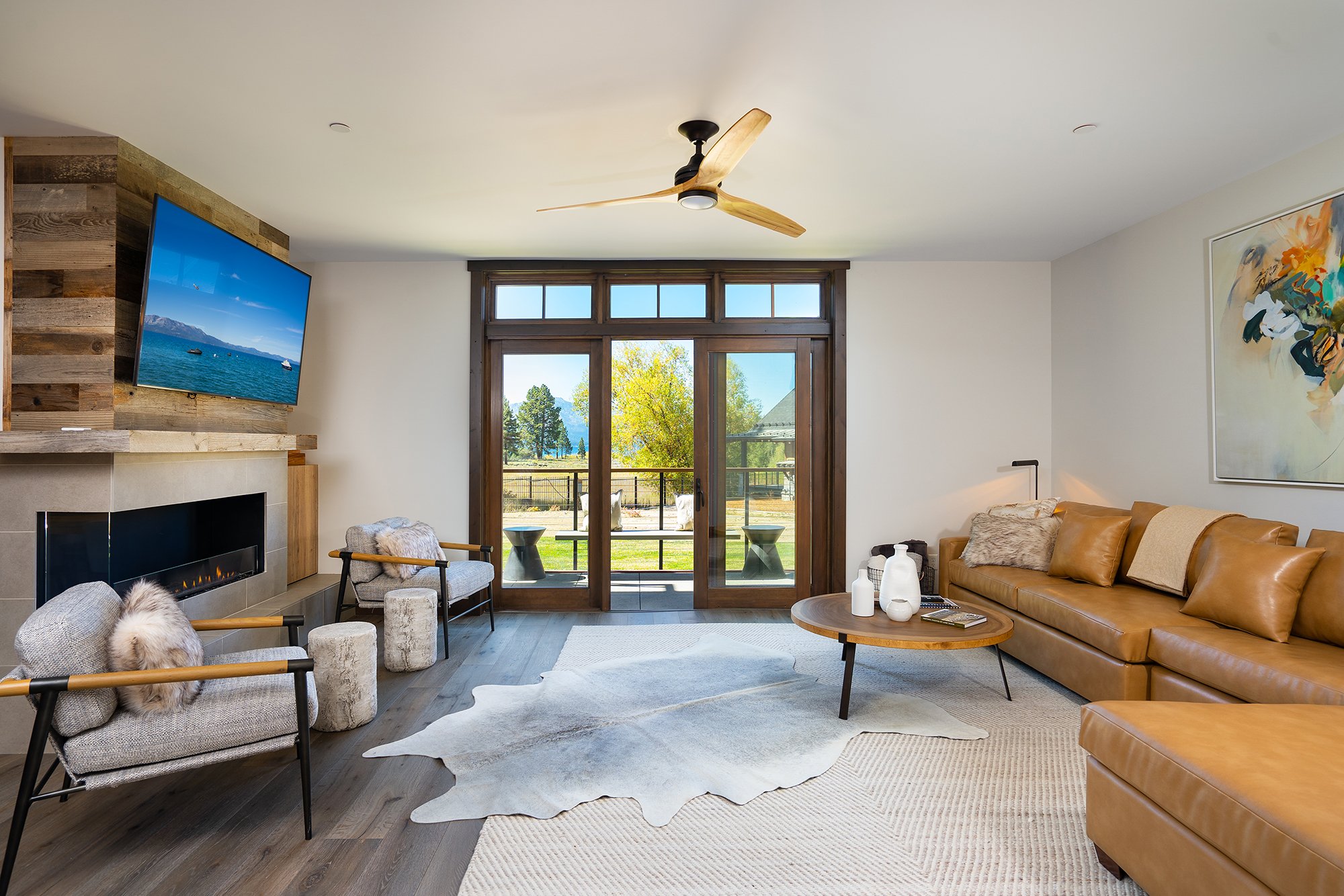  Modern living room featuring a large flat screen TV and a stylish sofa. Glass doors open up to a balcony overlooking the Tahoe landscape. 