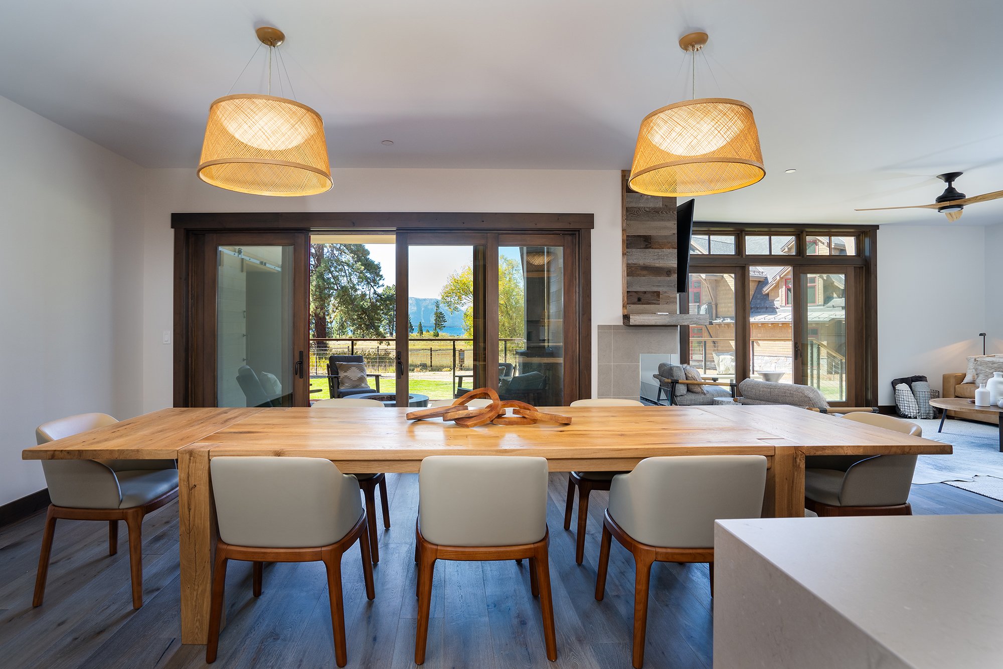 A spacious dining room with a long table surrounded by comfortable chairs. Large windows provide a scenic view of Tahoe. 