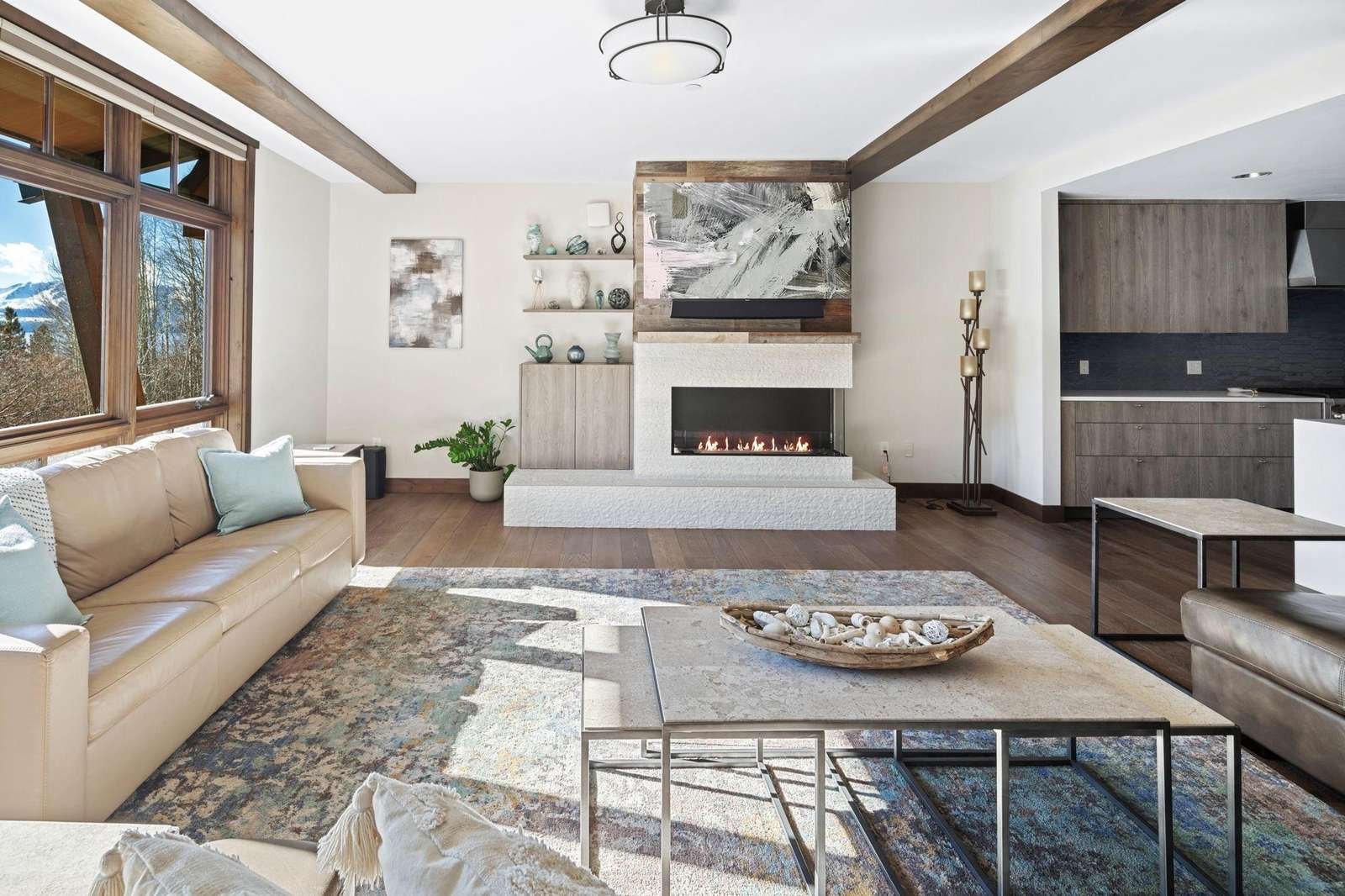 A cozy living room with a crackling fireplace and comfortable couches. Picture windows offer a view of Lake Tahoe. 
