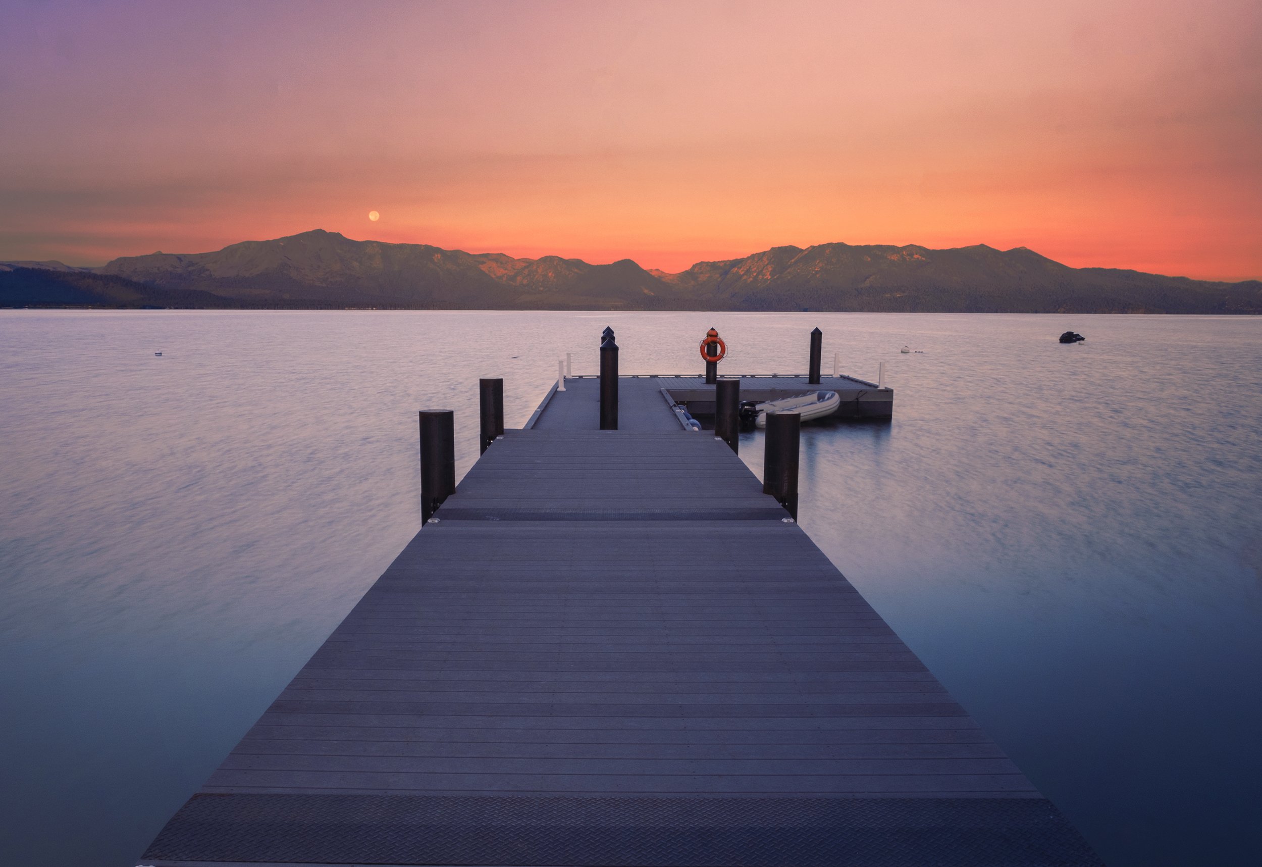 Sunset over Tahoe Beach Club's private dock, surrounded by the warm hues of the sky, offering a peaceful and scenic view of the tranquil waters of Lake Tahoe.