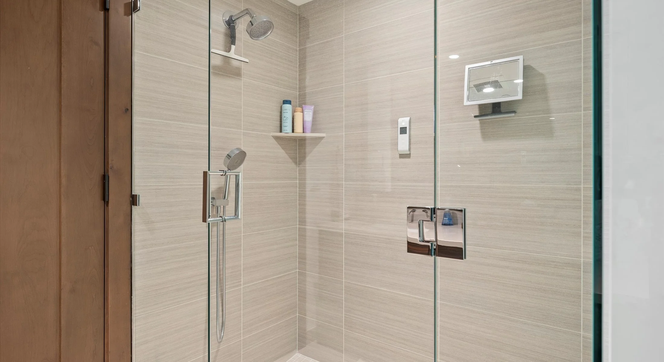 A modern bathroom showcasing a sizable glass enclosed shower with custom tiling, and modern lighting.  