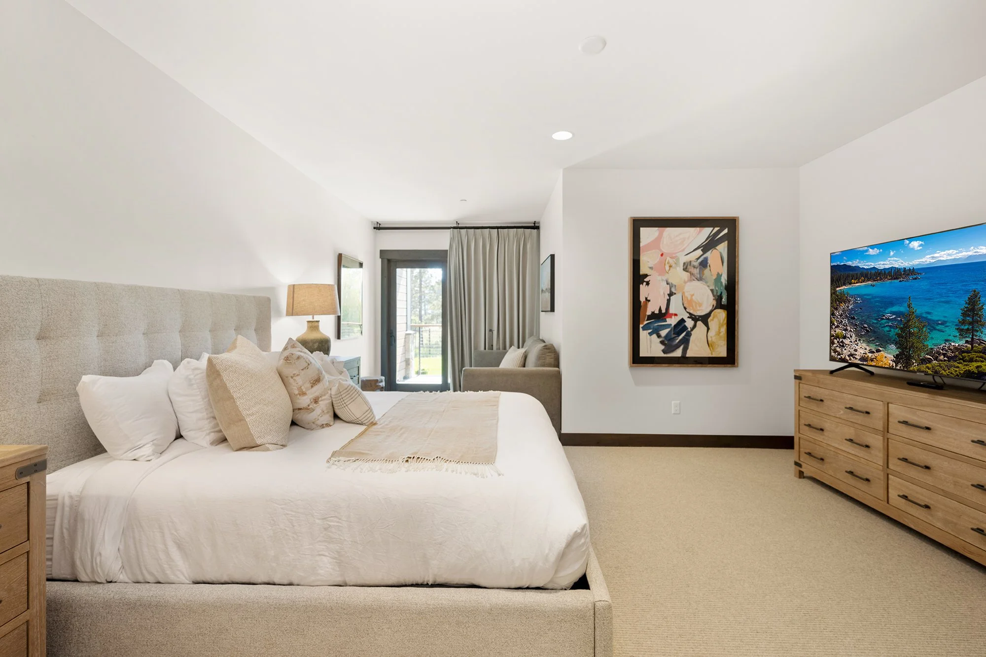 One of Residence 206's three modern bedrooms, featuring a large TV and bed.