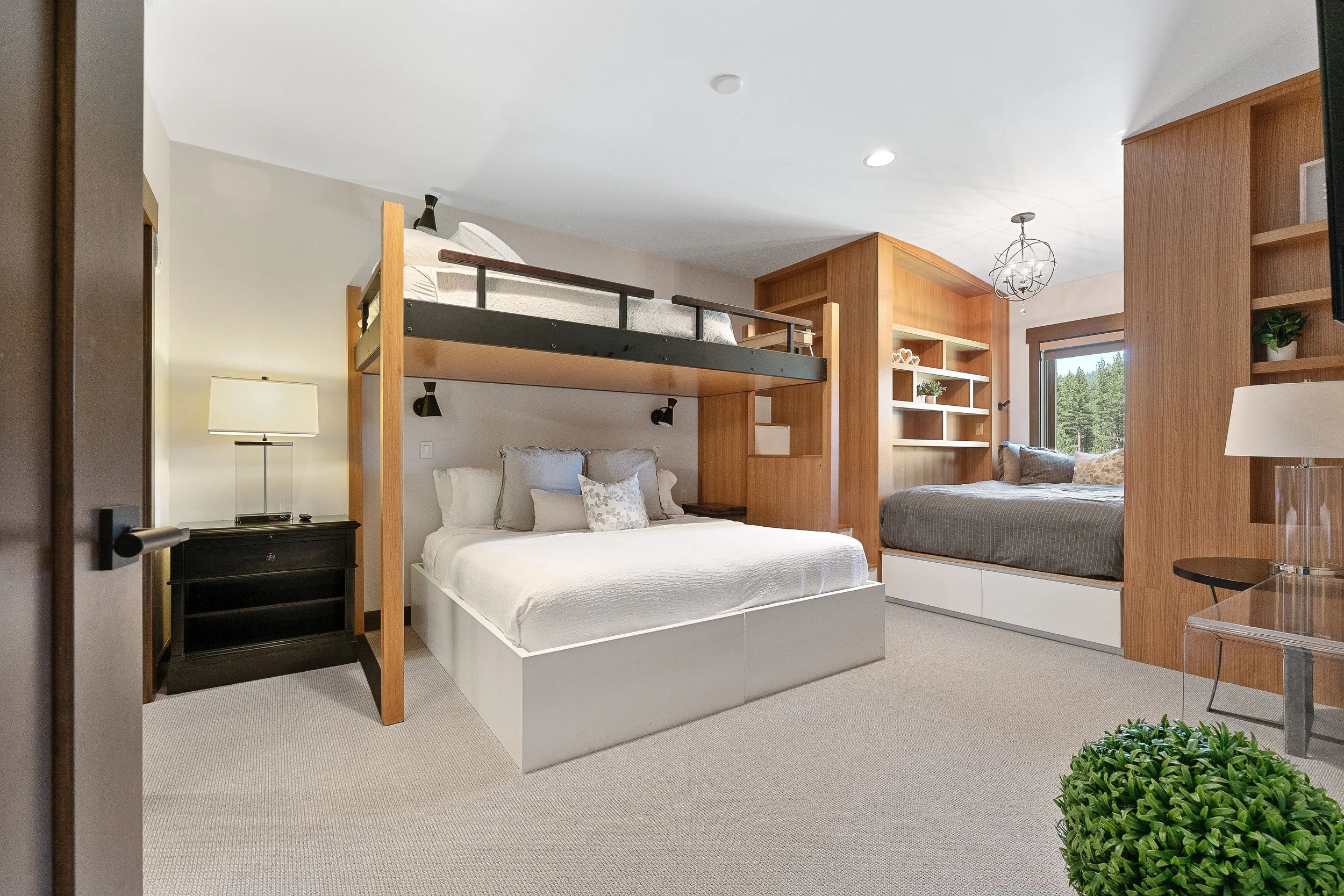 Large and bright bedroom boasts three cozy beds with built in bookcases, perfectly complementing the serene forest views through window