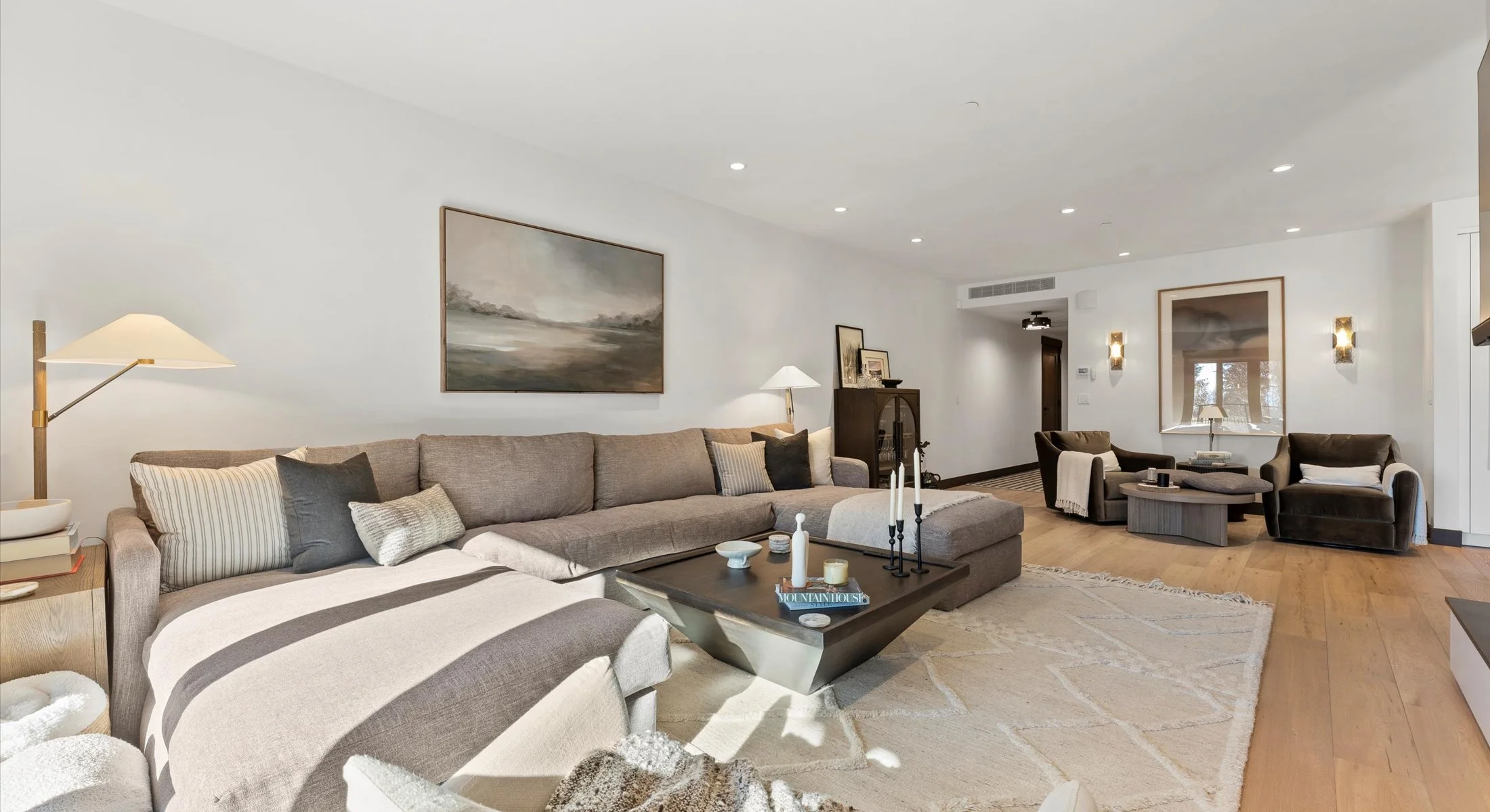 Residence 111's modern living living room feature stylish furniture, a mounted television, and a dual-sided fireplace. 