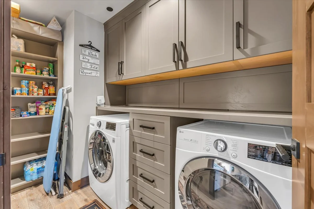 This large modern laundry room features generous cabinet storage and a high-quality LG washer and dryer, combining functionality with contemporary design for an efficient and organized space.
