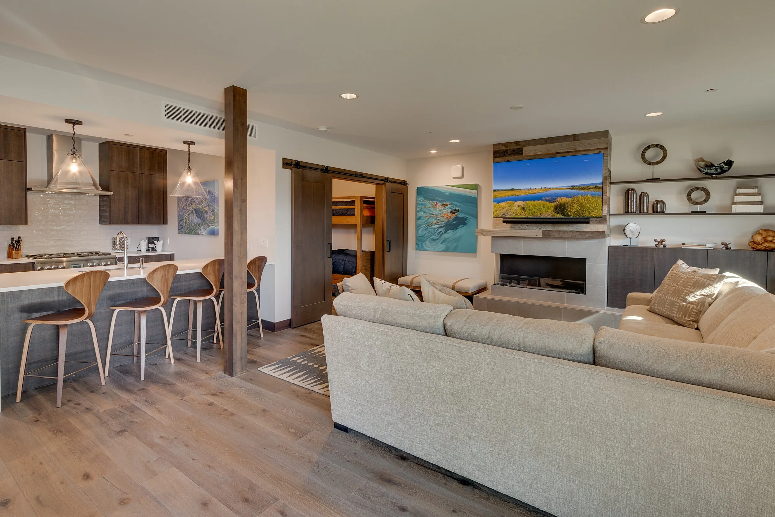 Vacation residence 216 features an open concept; a living room adorned with a cozy couch, a wall-mounted television, and an open kitchen.