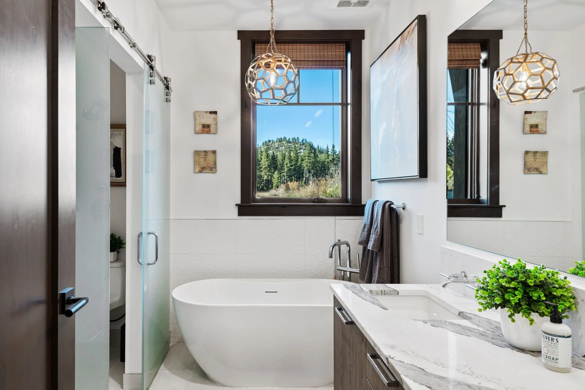Spacious Bathroom with Double Vanity, Glass-Enclosed Shower, Barn-Style Doors, and Custom Stone Tiles