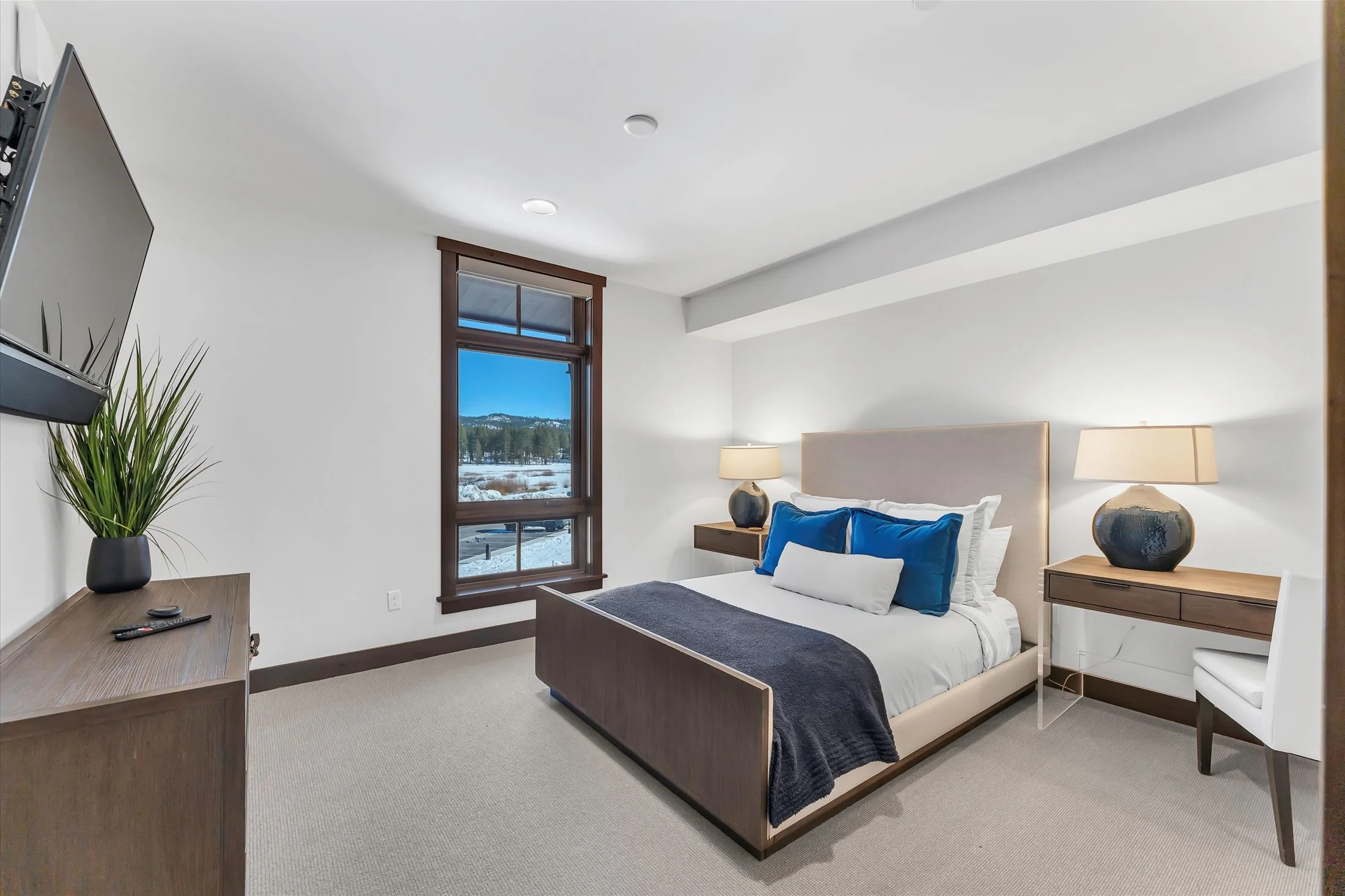 Bright Tahoe Beach Club bedroom featuring modern, cozy décor and a large window with views of the forest.