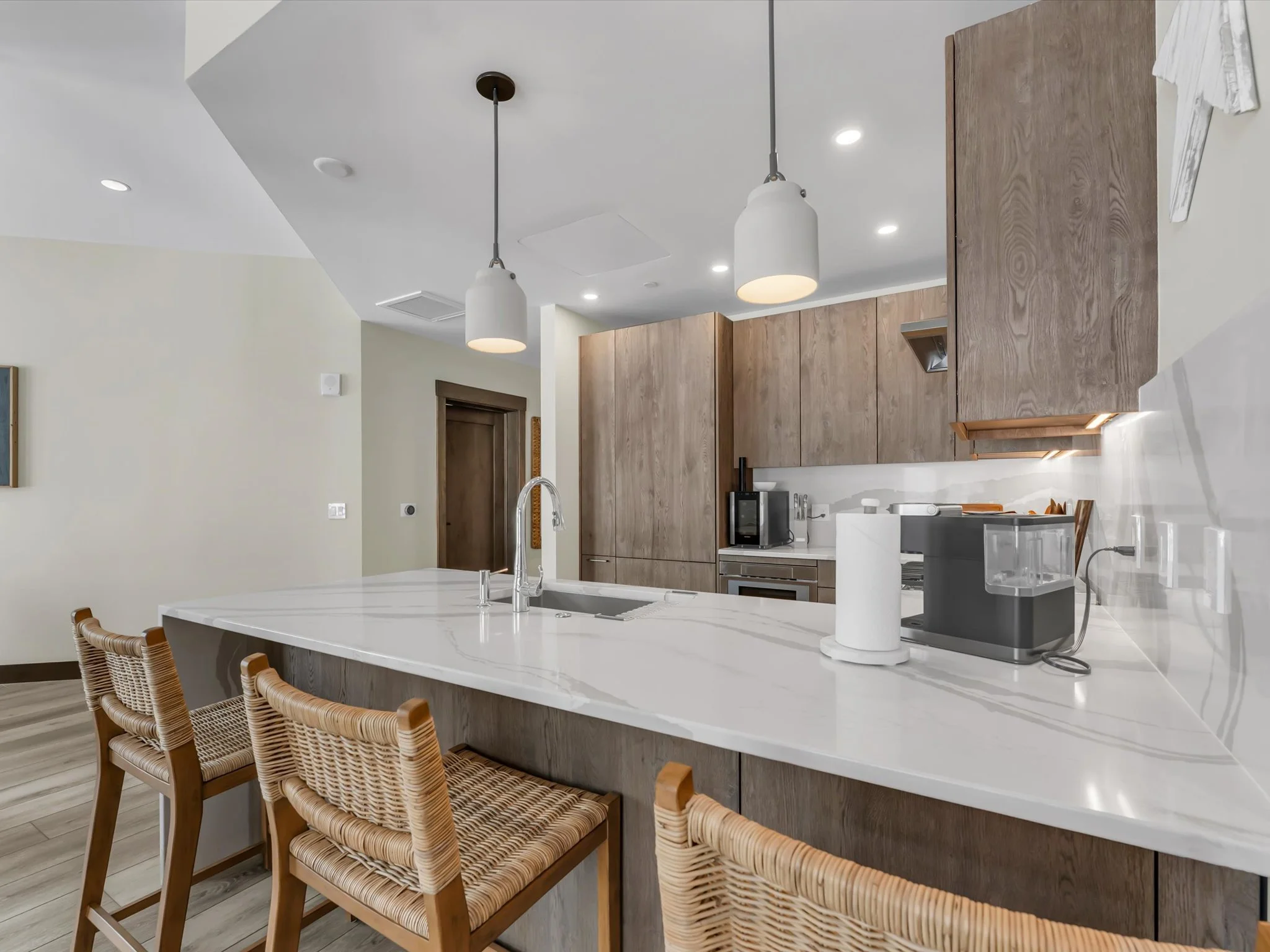 Tahoe Beach Club residence 902 includes a modern kitchen with a sleek marble island and stylish bar stools, creating a sophisticated and inviting space.
