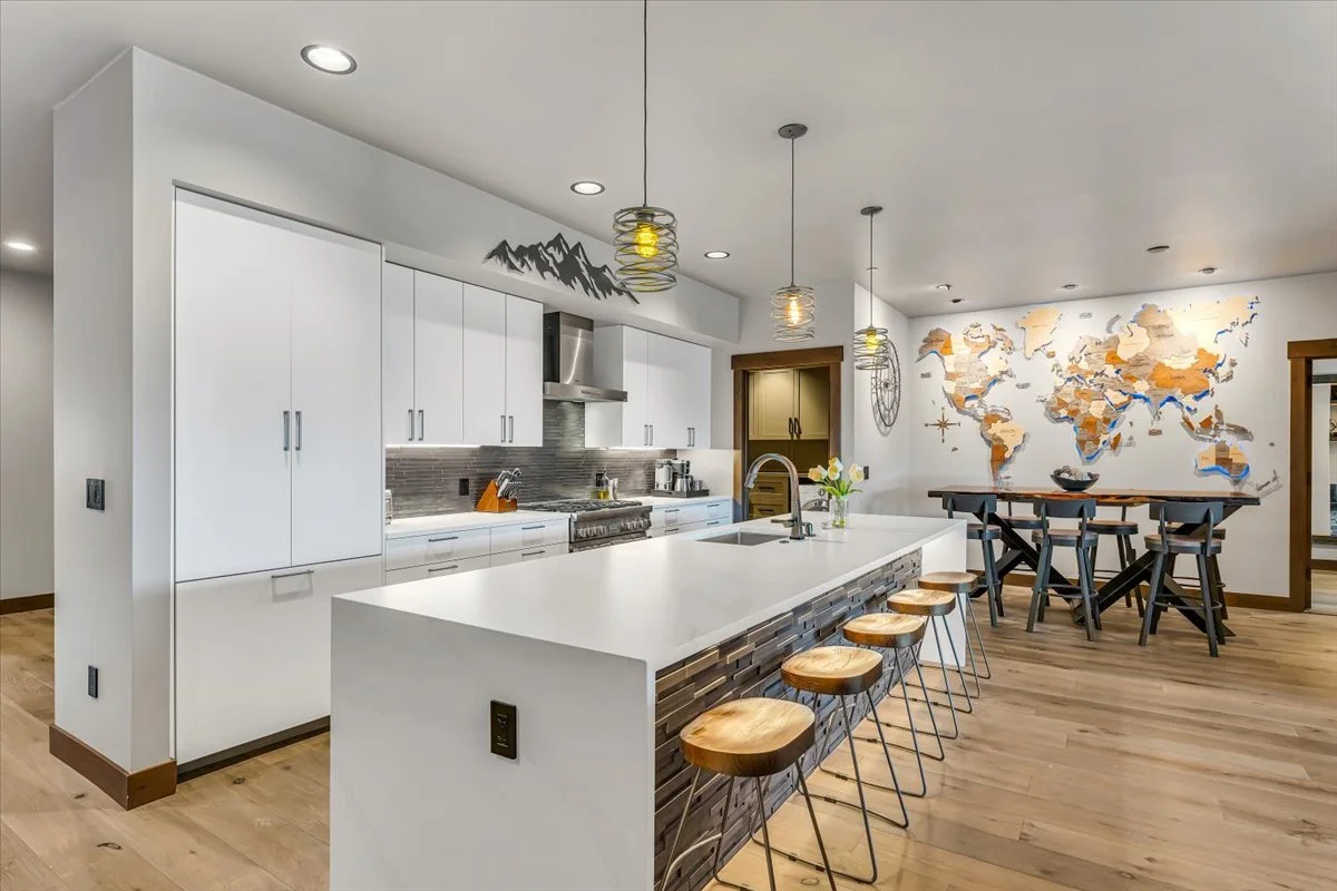 Bright open-concept floor plan featuring a kitchen with modern appliances, dining area and living area seamlessly connected with hardwood floors, and abundant indoor and natural light.