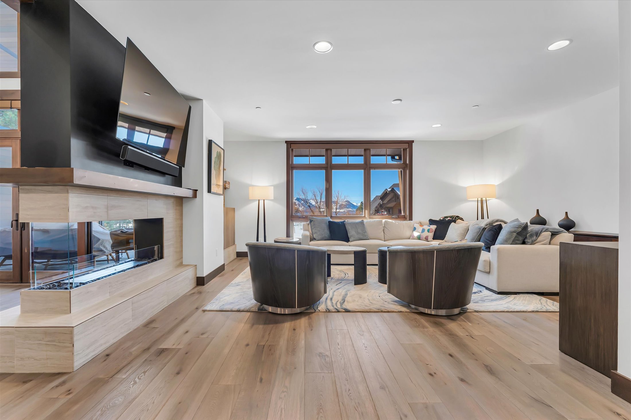 A cozy Tahoe Beach Club living room with a modern design, dual-sided fireplace, abundant natural light, and hardwood floors throughout.