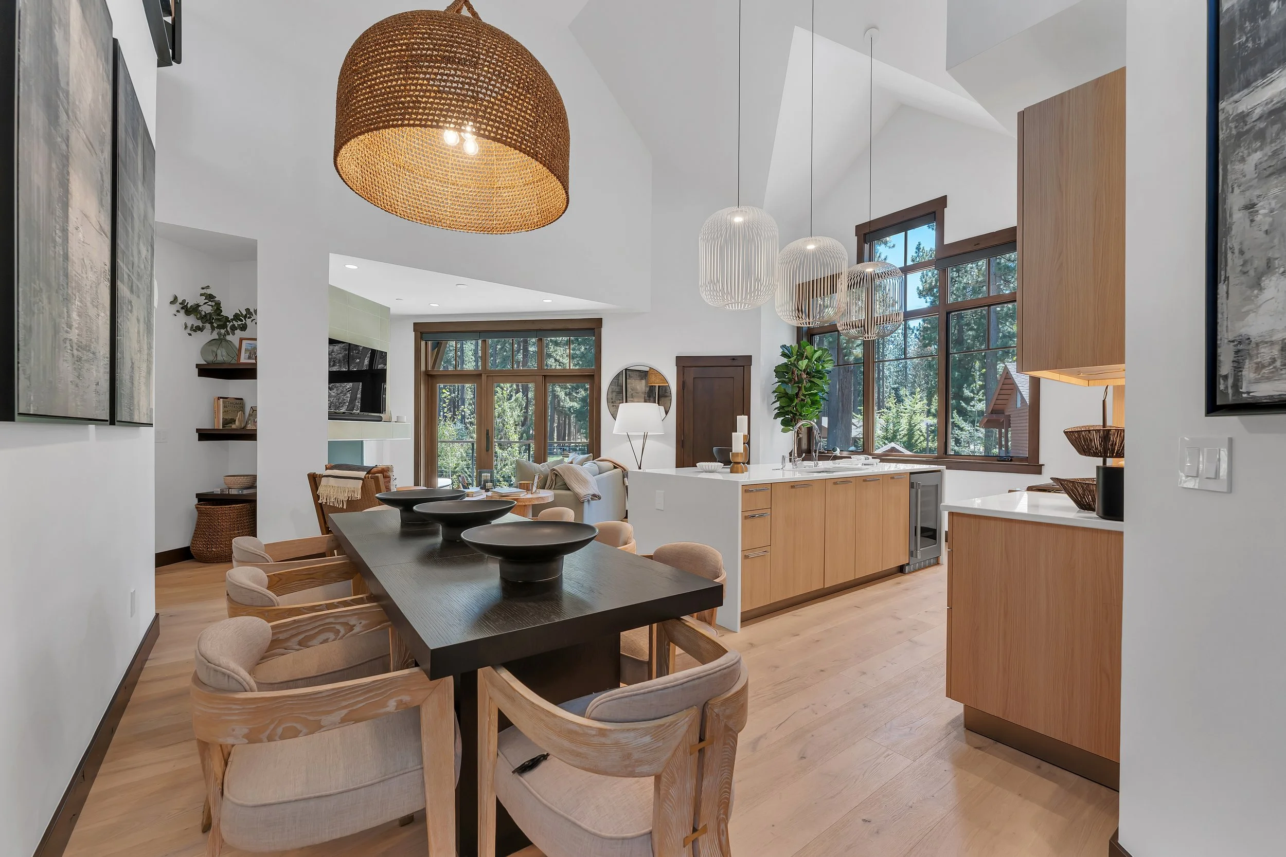 Elegantly designer-furnished, this open-concept kitchen, dining, and living area features light wood cabinetry, stainless steel appliances, hardwood floors throughout, and expansive windows that fill the space with natural light. A generous dining ta