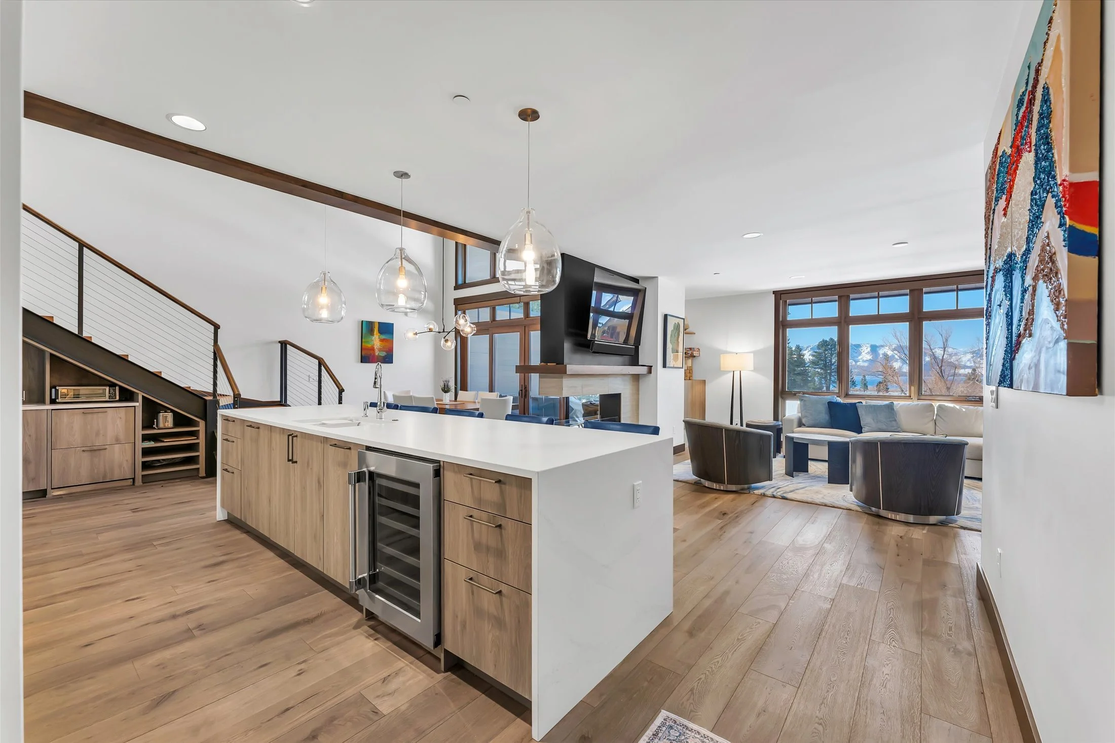 Bright open-style floor plan with kitchen and living areas, elegant finishes, hardwood floors throughout and large glass doors leading out to a private patio with scenic Tahoe views.