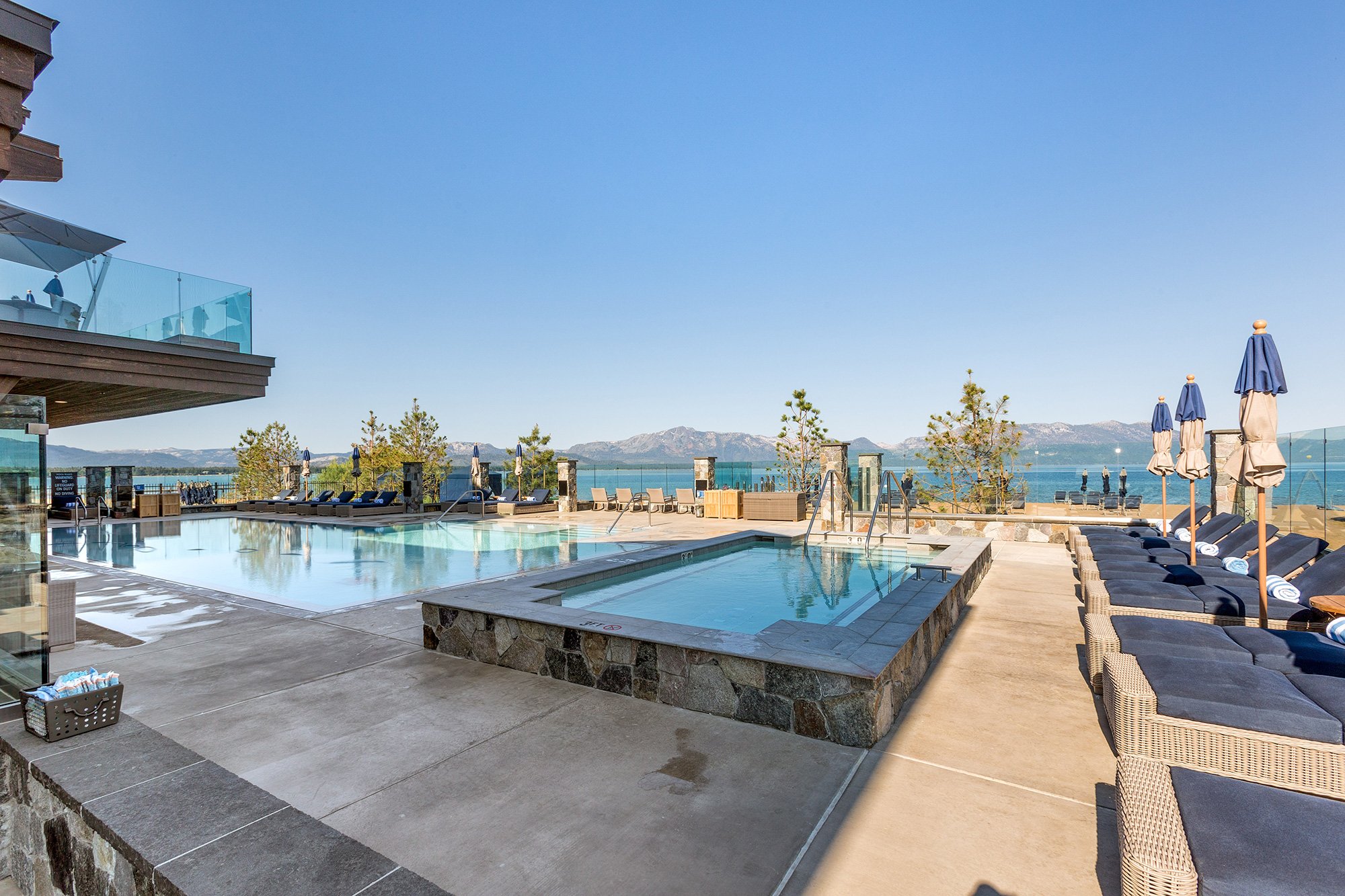 Relaxing pool area at the lakefront resort, showcasing a stunning view of serene Lake Tahoe and the surrounding Sierras.