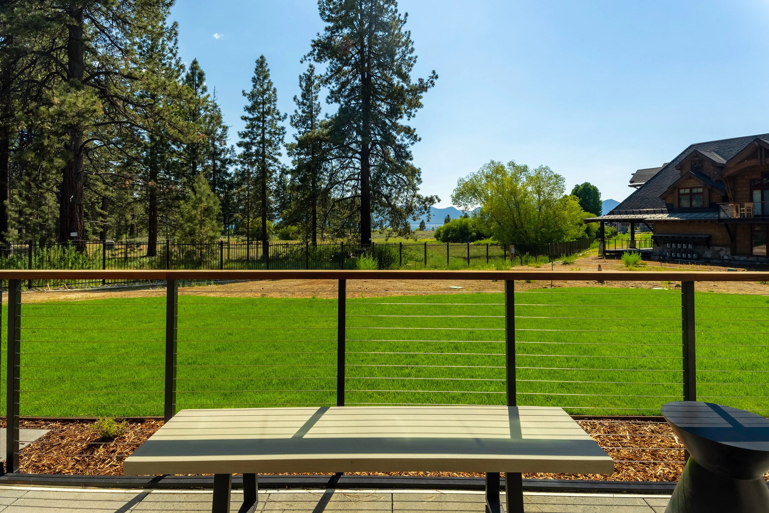 A wooden bench on a deck, providing a scenic view of Tahoe Beach Club and the surrounding Tahoe landscape.