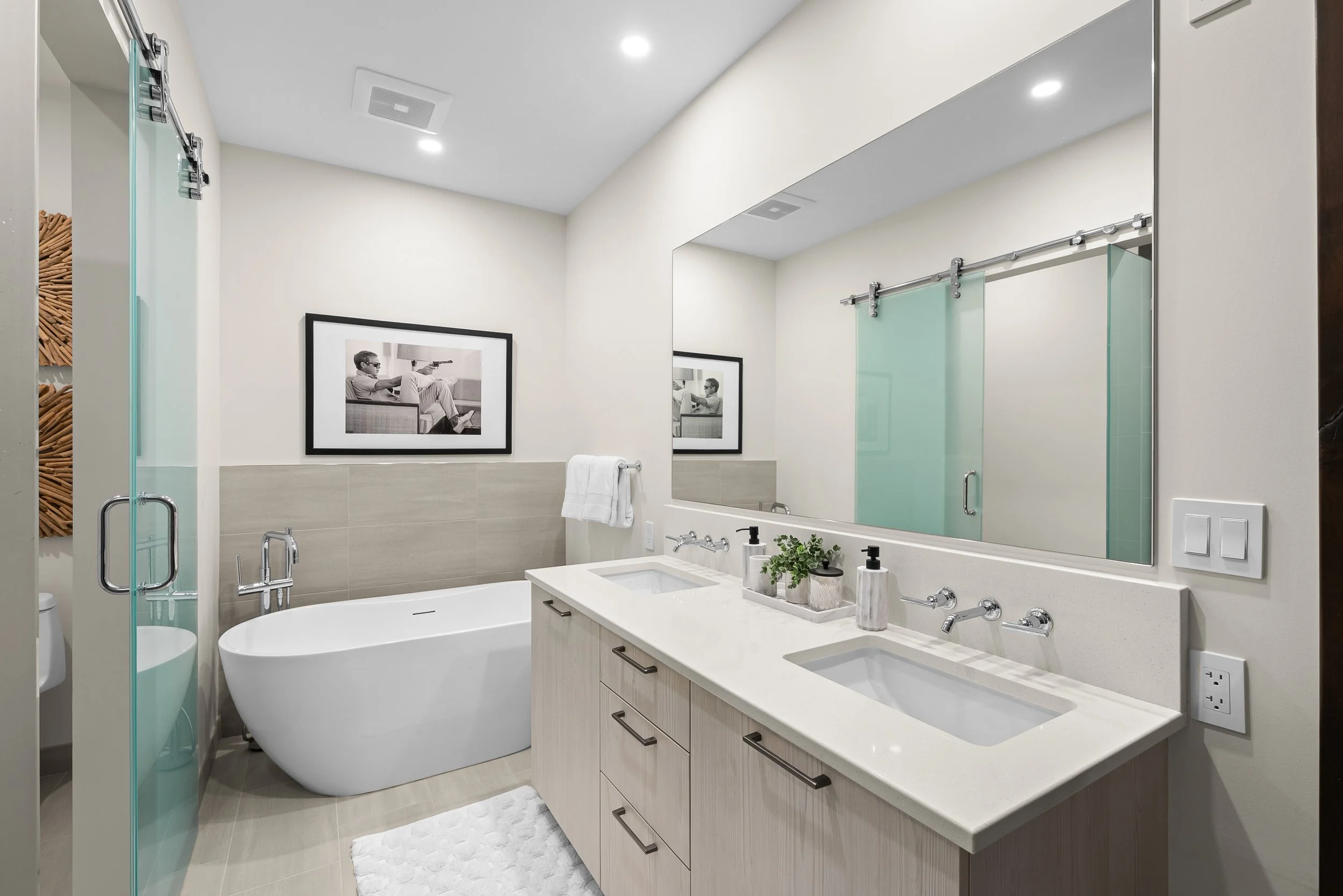 Modern bathroom at Tahoe Beach Club featuring a free standing bathtub, a double vanity with sleek fixtures, a class-enclosed shower, and natural wood accents.