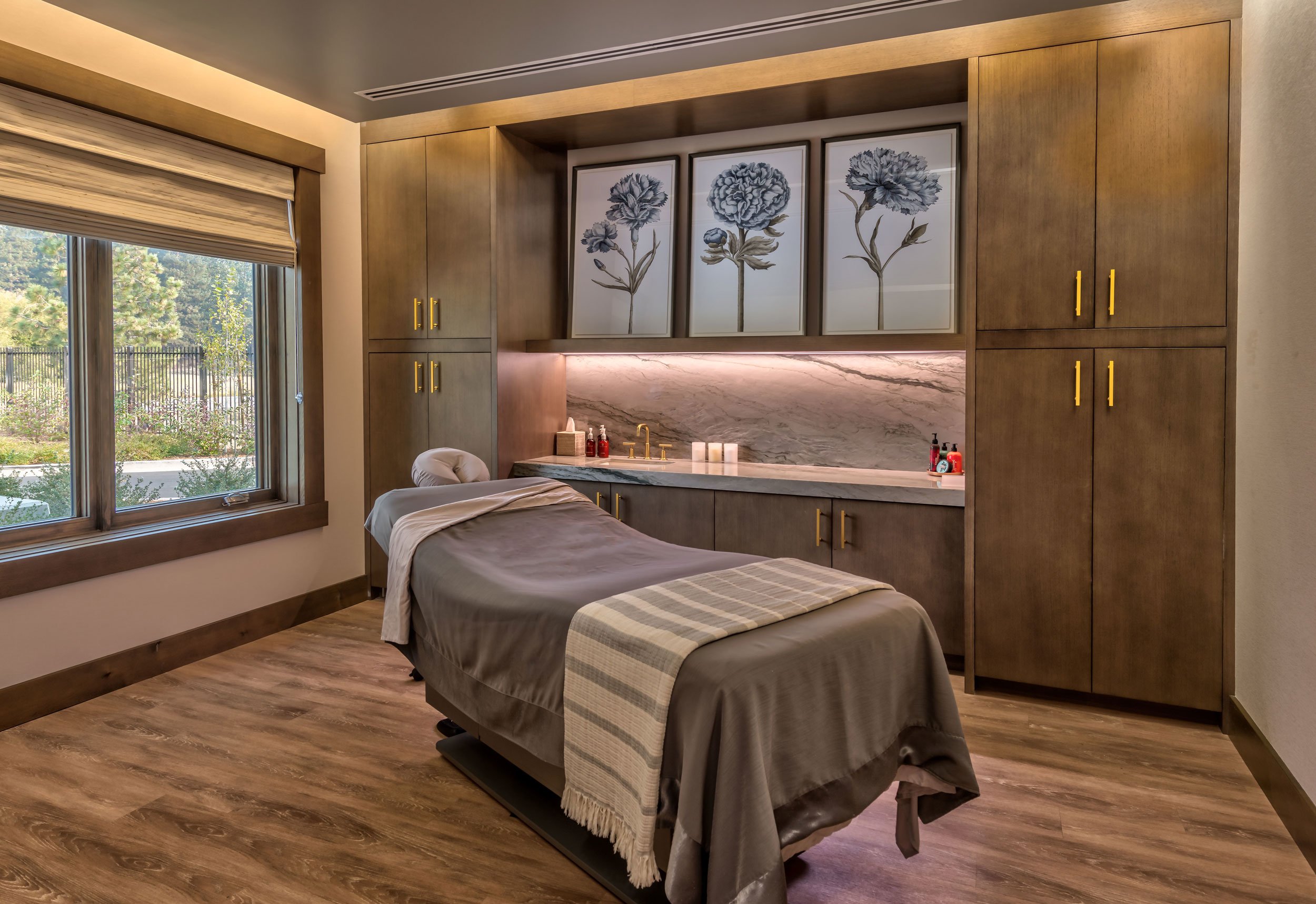 Tahoe Beach Club's spa features a tranquil massage room with a wooden floor and ample natural light from a large window.