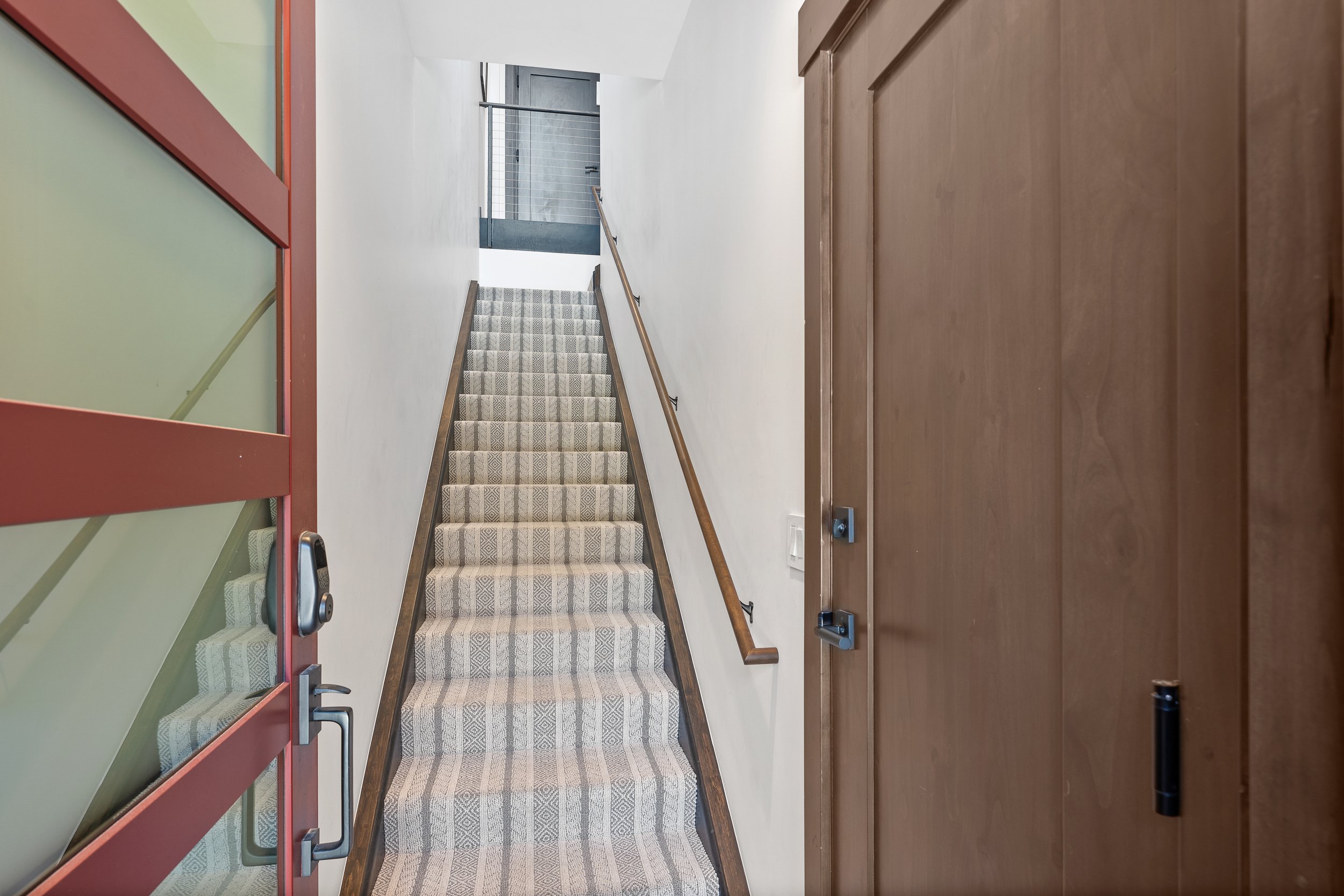 The home’s main level welcomes you with a sleek open staircase, modern cable railing, and warm wood floors. Just beyond, the dining and living areas flow seamlessly in an open-concept design. Wide walkways and flush thresholds support easy navigation