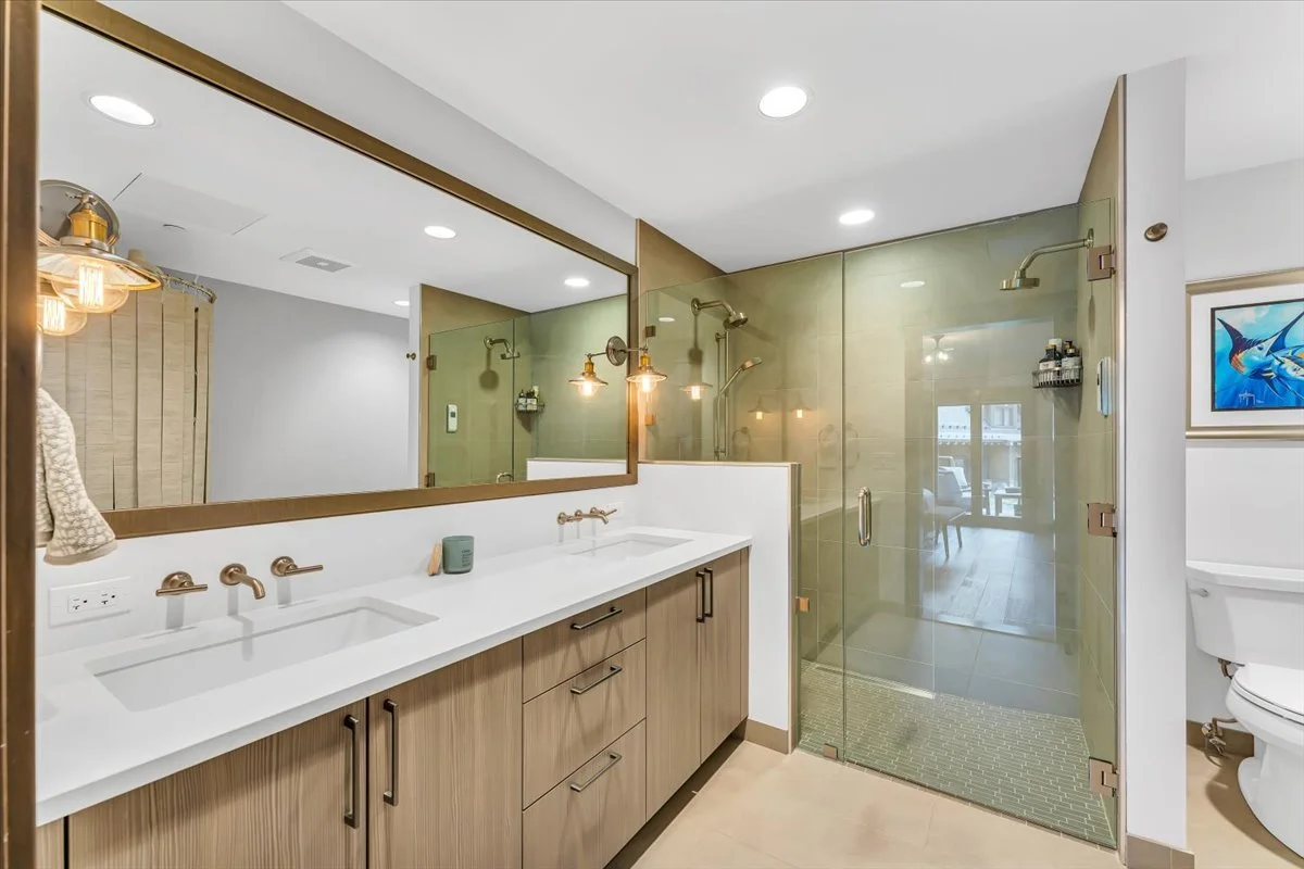 Modern bathroom featuring a glass-enclosed shower, double vanity with a large mirror, and custom tile finishes for a clean, elegant, and functional design.