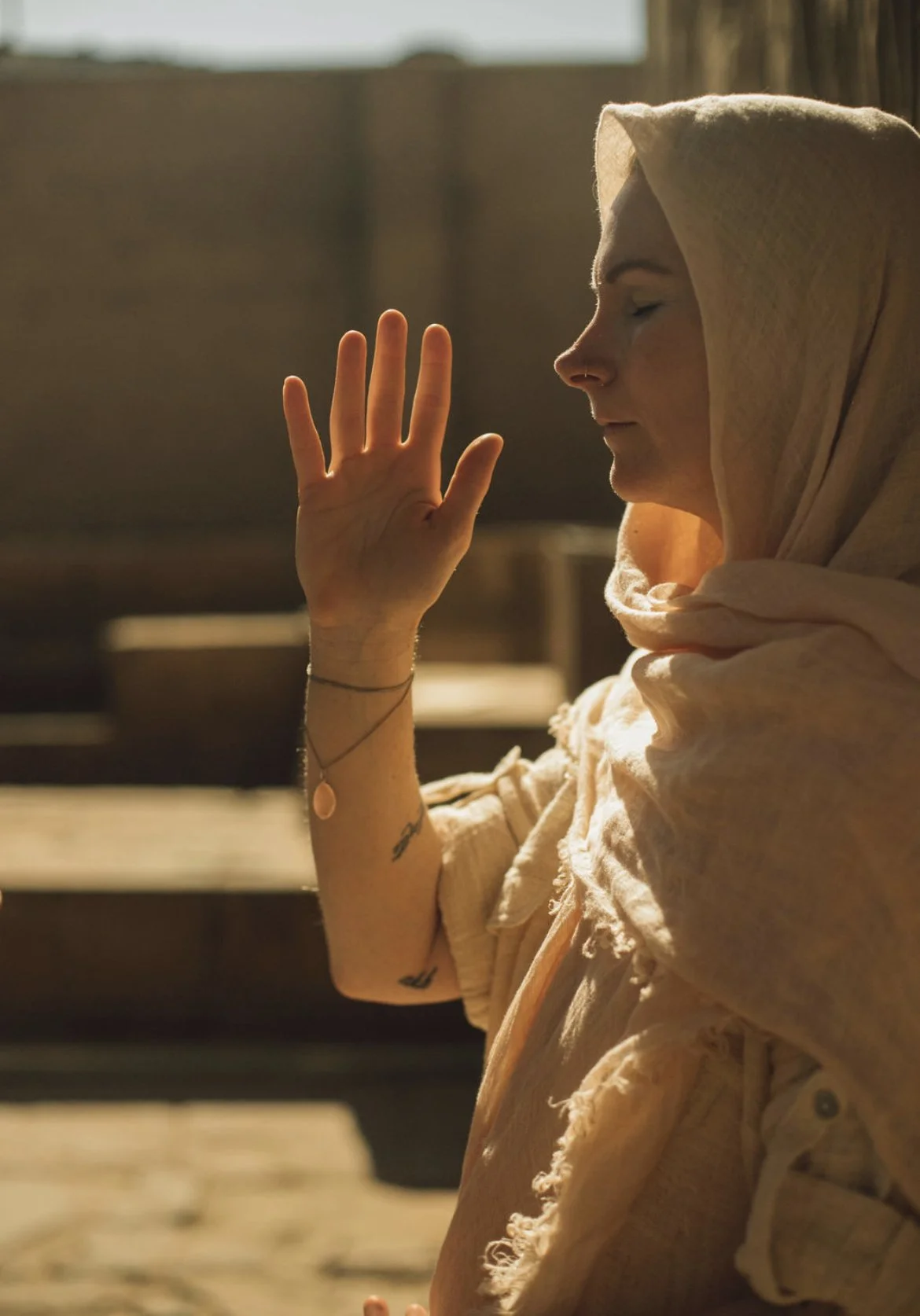 Casey Castro standing in warm sunlight in Egypt, eyes closed and hand raised.