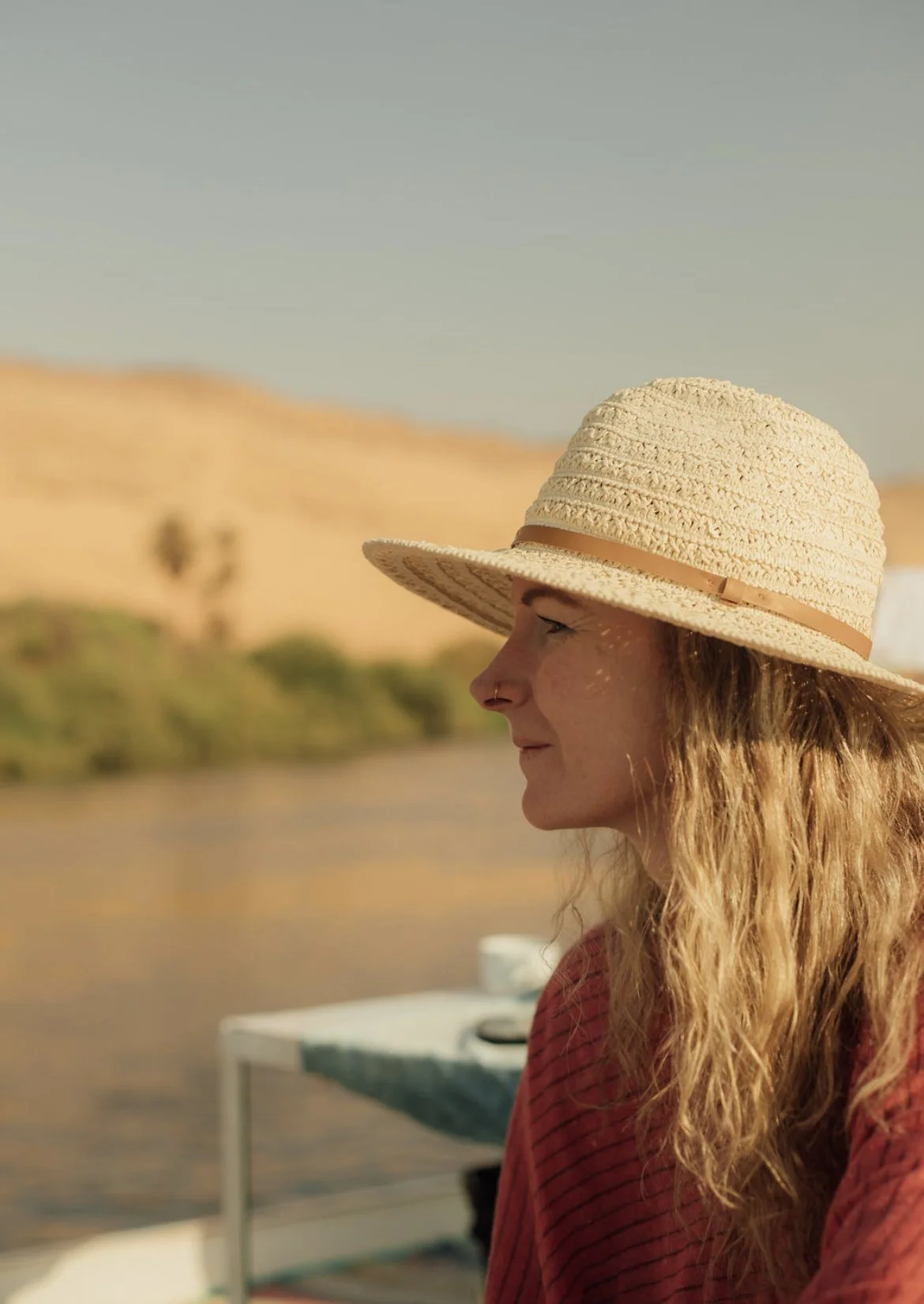 Casey Castro aboard a boat on the Nile in Egypt, wearing a straw hat in warm natural light.