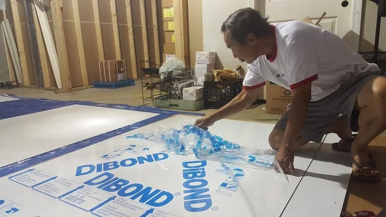 Hung is unwrapping a new board with Tony (off camera) to prep for the sanding process. (Photo: Kathy)