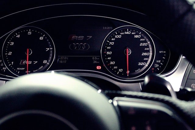 Close-up of an Audi RS7 dashboard with speedometer, tachometer, and digital display showing the Audi logo.