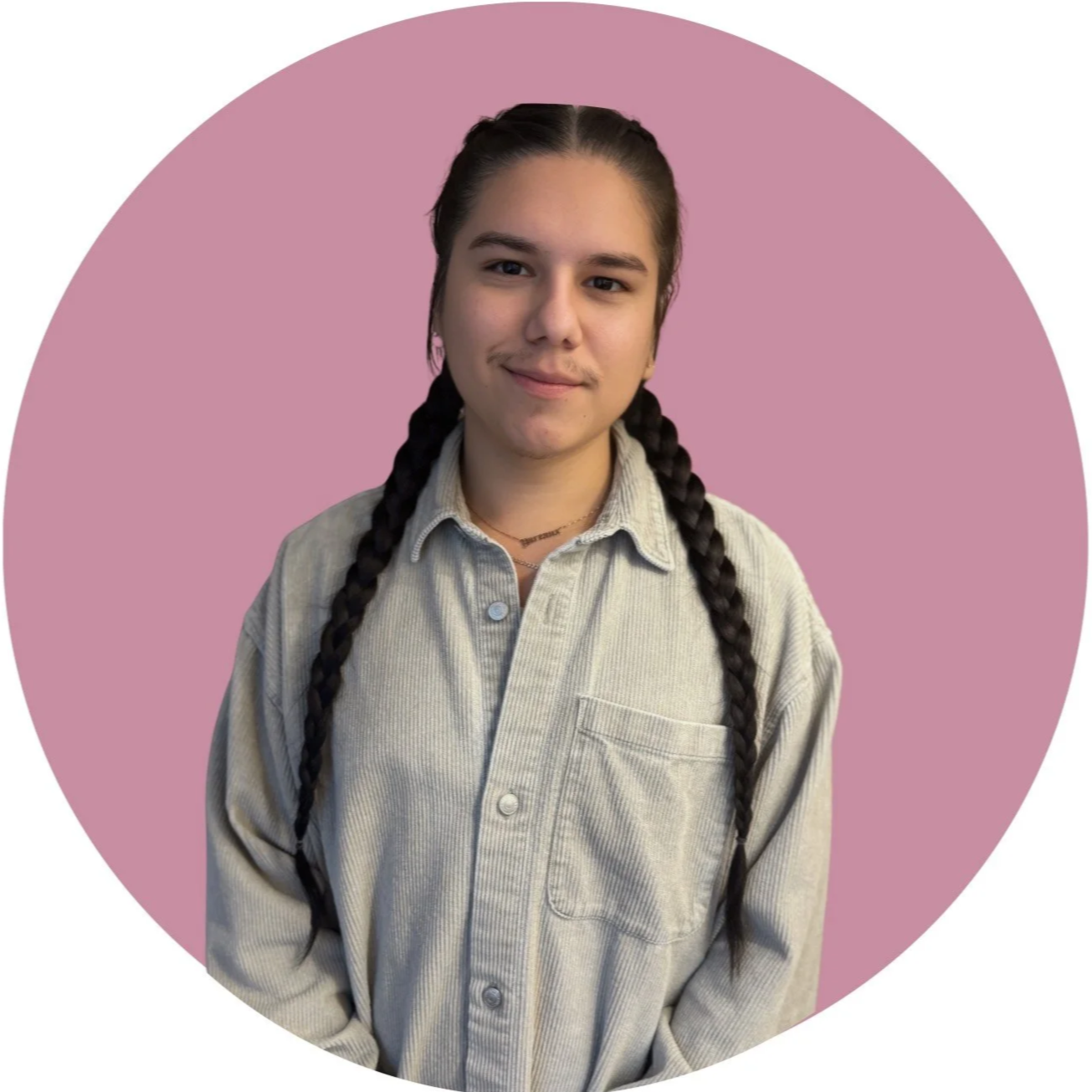 A young man with long dark hair, wearing a baseball cap backwards and a white t-shirt, standing in a room with beige walls.