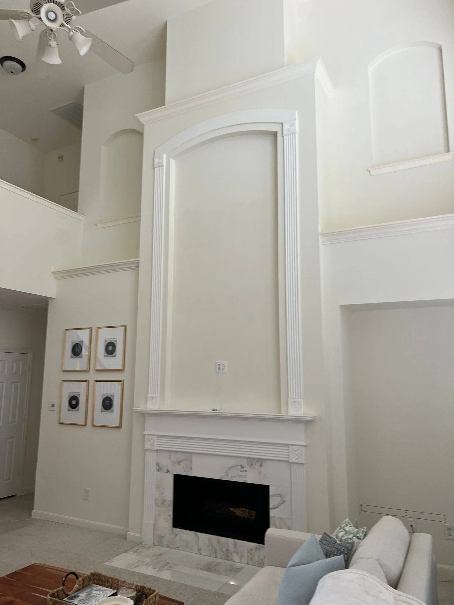 Freshly painted two-story living room with off-white walls, painted mantle, and trim in Sugar Land, Texas