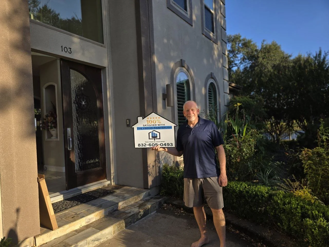 Freshly painted stucco exterior with satisfied homeowner holding sign in Sugar Land, Texas