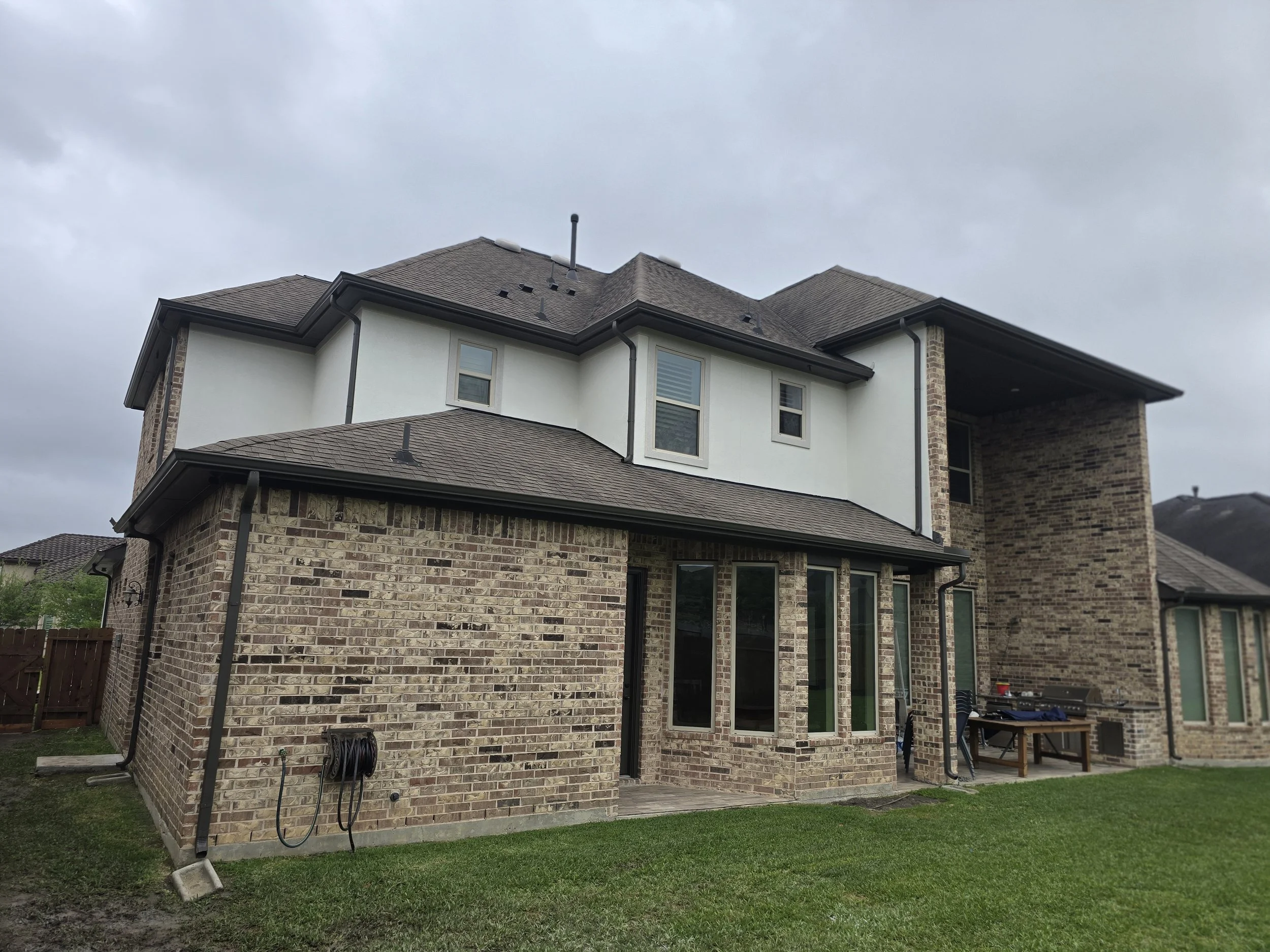 Rear exterior painting project in Fulshear TX showing brick home with painted trim, soffits, and gutters
