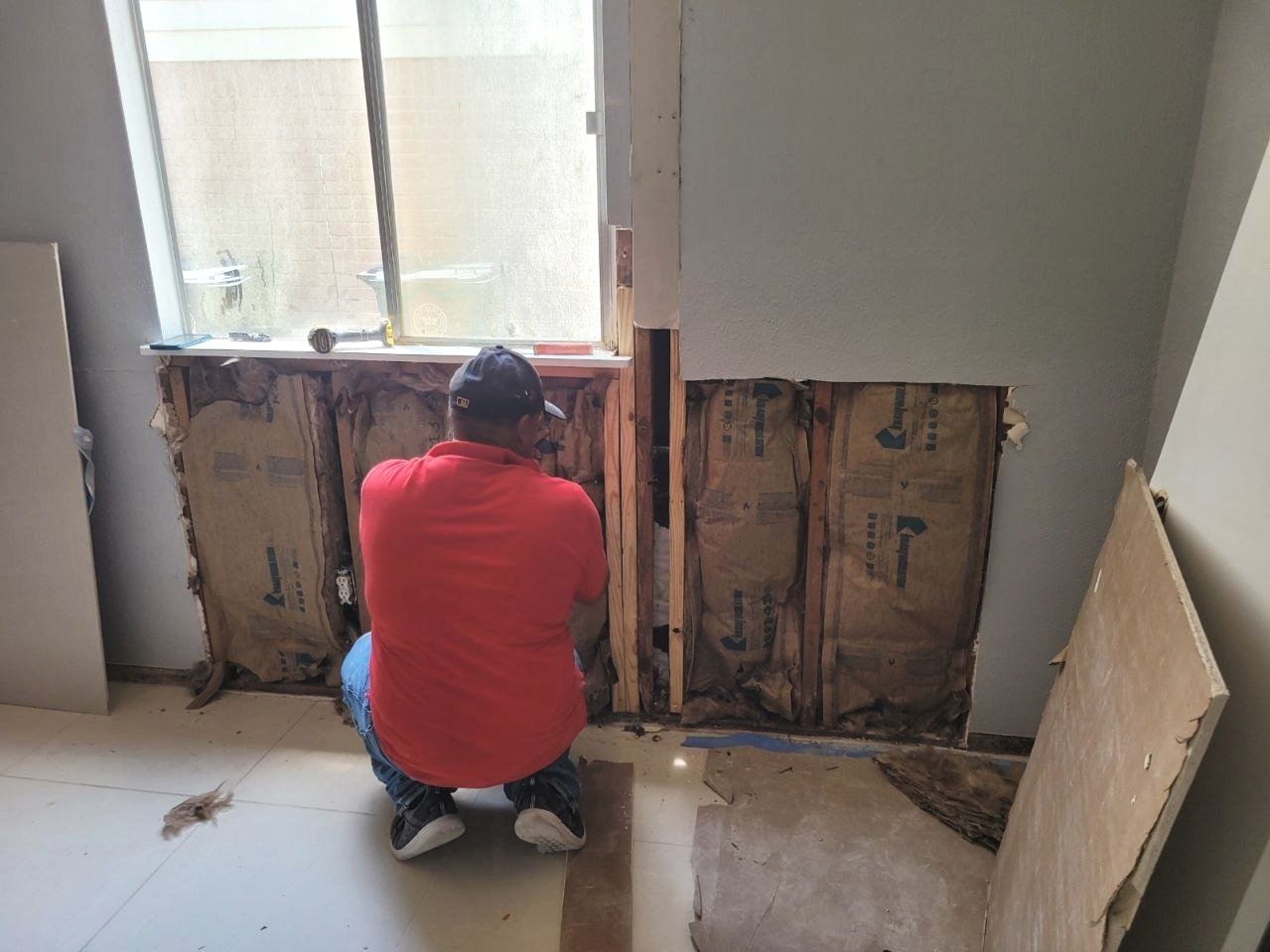 Professional drywaller opening a wall and taking measurements to replace a piece of drywall in Sugar Land, Texas.