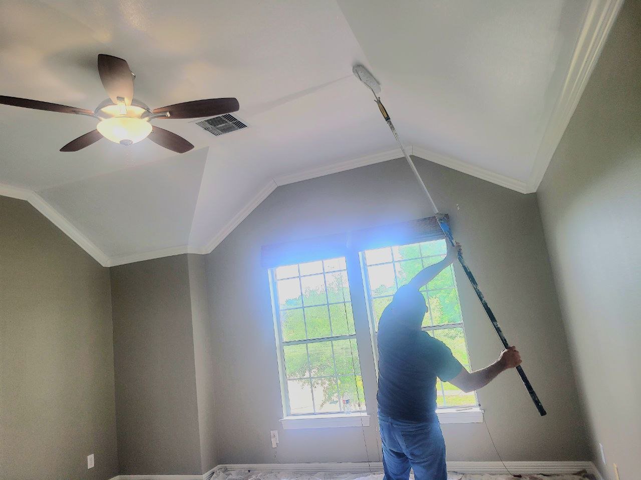 Professional painter rolling a ceiling in a freshly painted interior home in Missouri City, Texas.