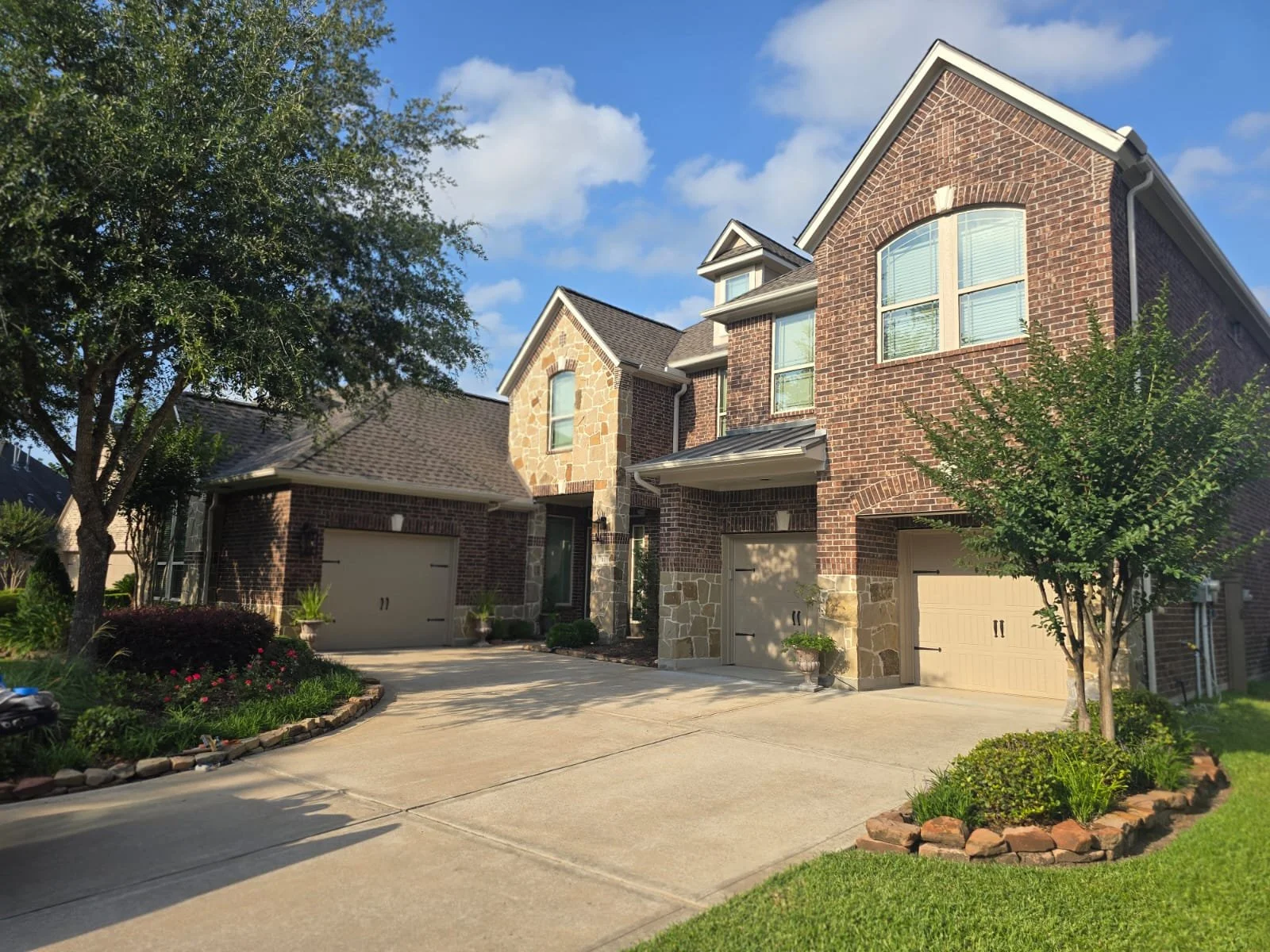 Freshly painted brick exterior with trim, garage doors, and hardy board in West Houston, Texas