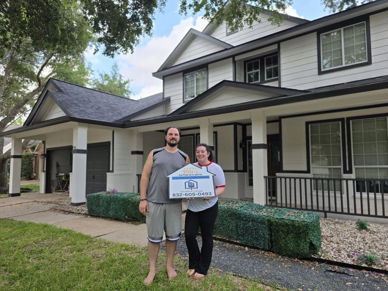 Satisfied Richmond homeowner holding a 100 percent satisfied sign in front of a freshly painted black and white exterior